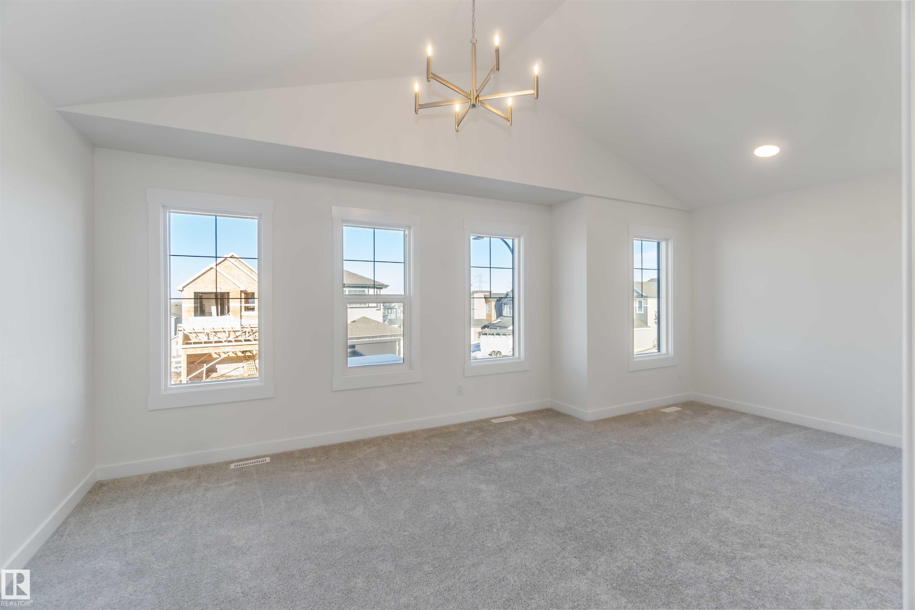 Spare room with a chandelier, light carpet, vaulted ceiling, and healthy amount of natural light - 2215 4 Avenue, Edmonton, AB - Indoor Photo Showing Other Room