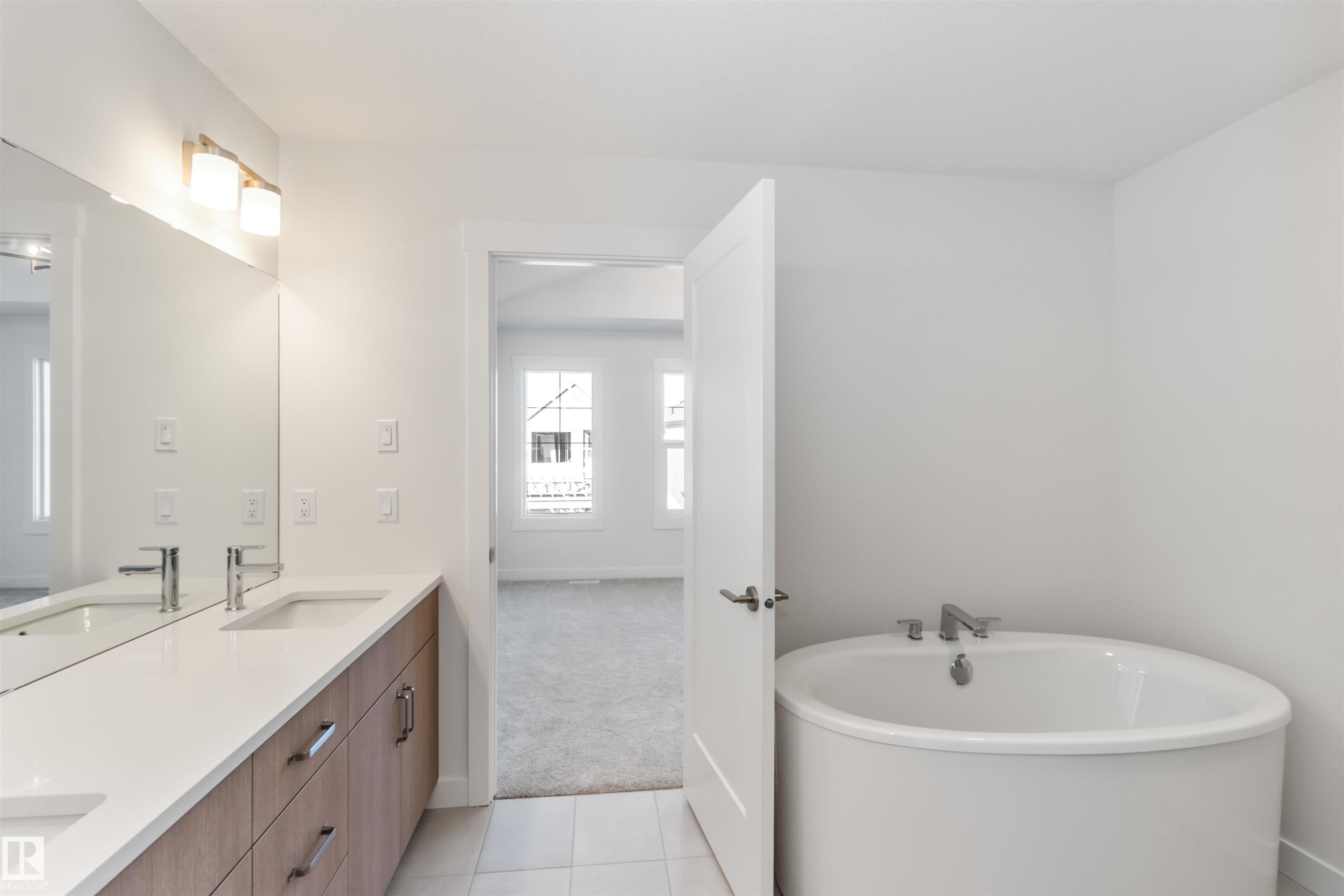 Bathroom featuring double vanity, a soaking tub, light tile patterned flooring, and light colored carpet - 2215 4 Avenue, Edmonton, AB - Indoor Photo Showing Bathroom