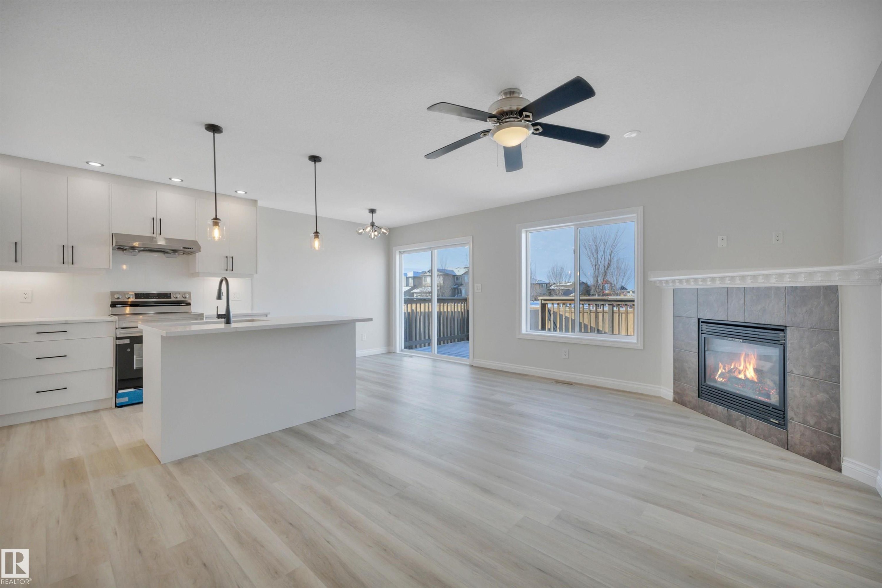 Unfurnished living room with a fireplace, light wood-type flooring, recessed lighting, and ceiling fan - 457 Aster Close, Leduc, AB - Indoor With Fireplace