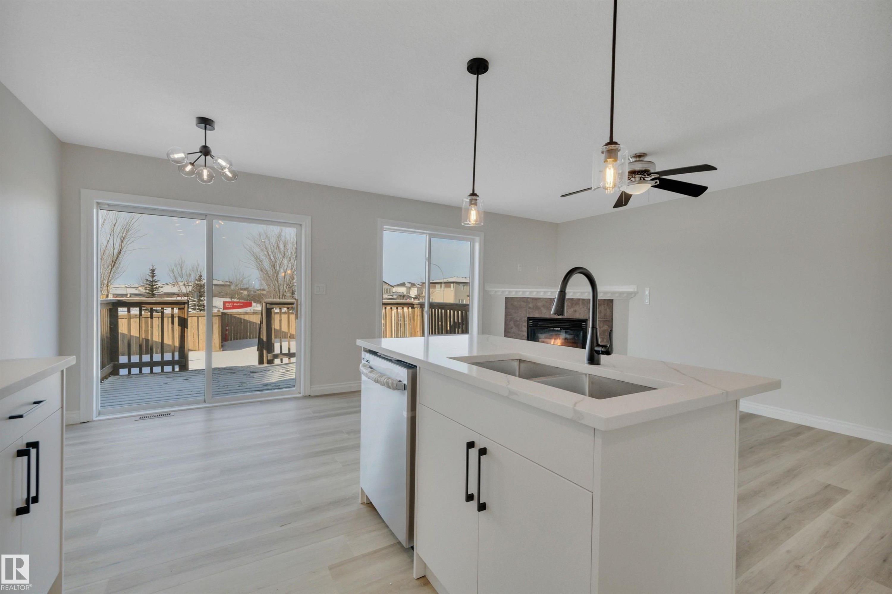 Kitchen with white cabinets, dishwashing machine, light wood finished floors, and a chandelier - 457 Aster Close, Leduc, AB - Indoor Photo Showing Kitchen With Double Sink