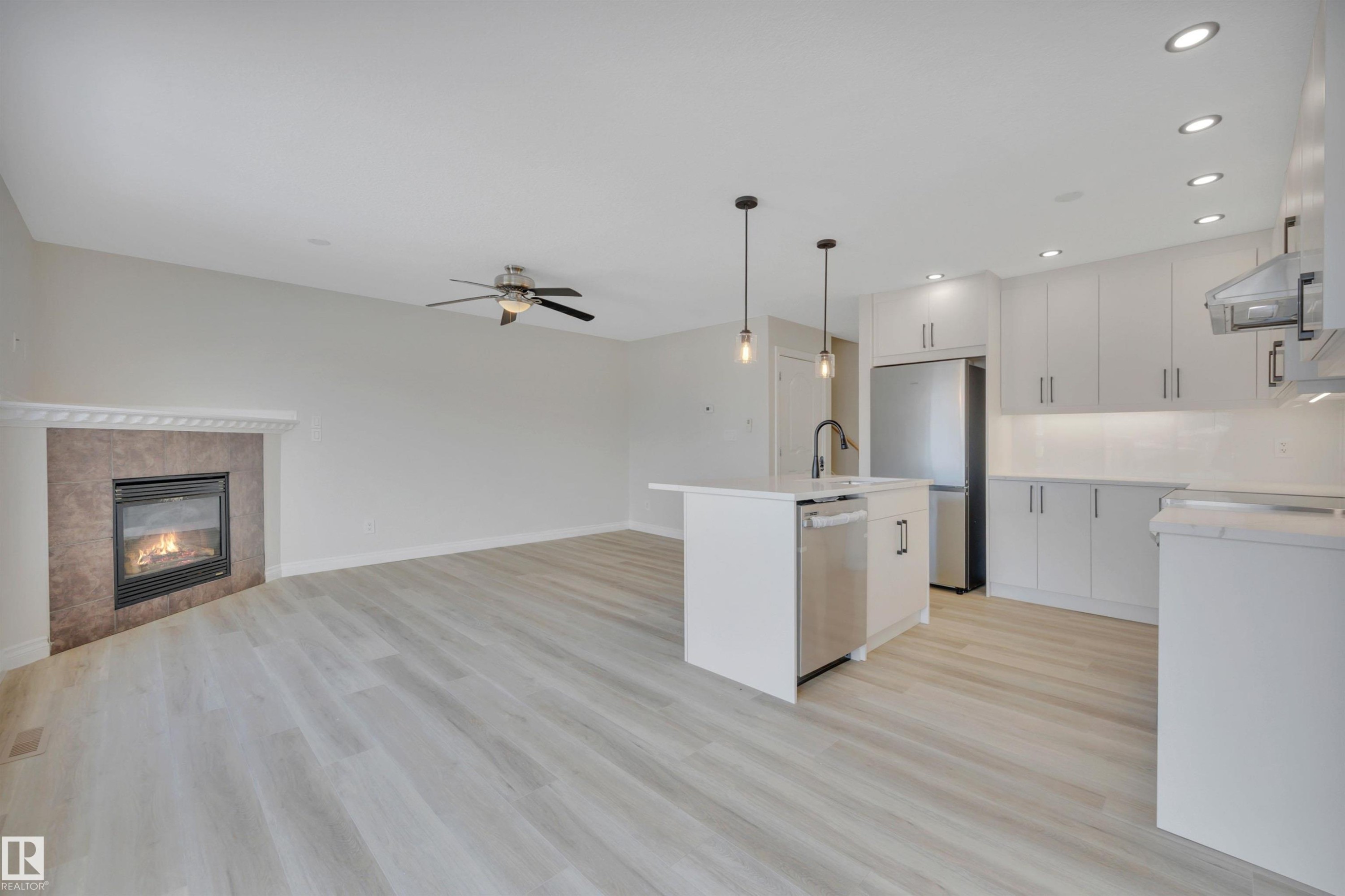 Kitchen with white cabinetry, an island with sink, open floor plan, recessed lighting, and pendant lighting - 457 Aster Close, Leduc, AB - Indoor Photo Showing Kitchen