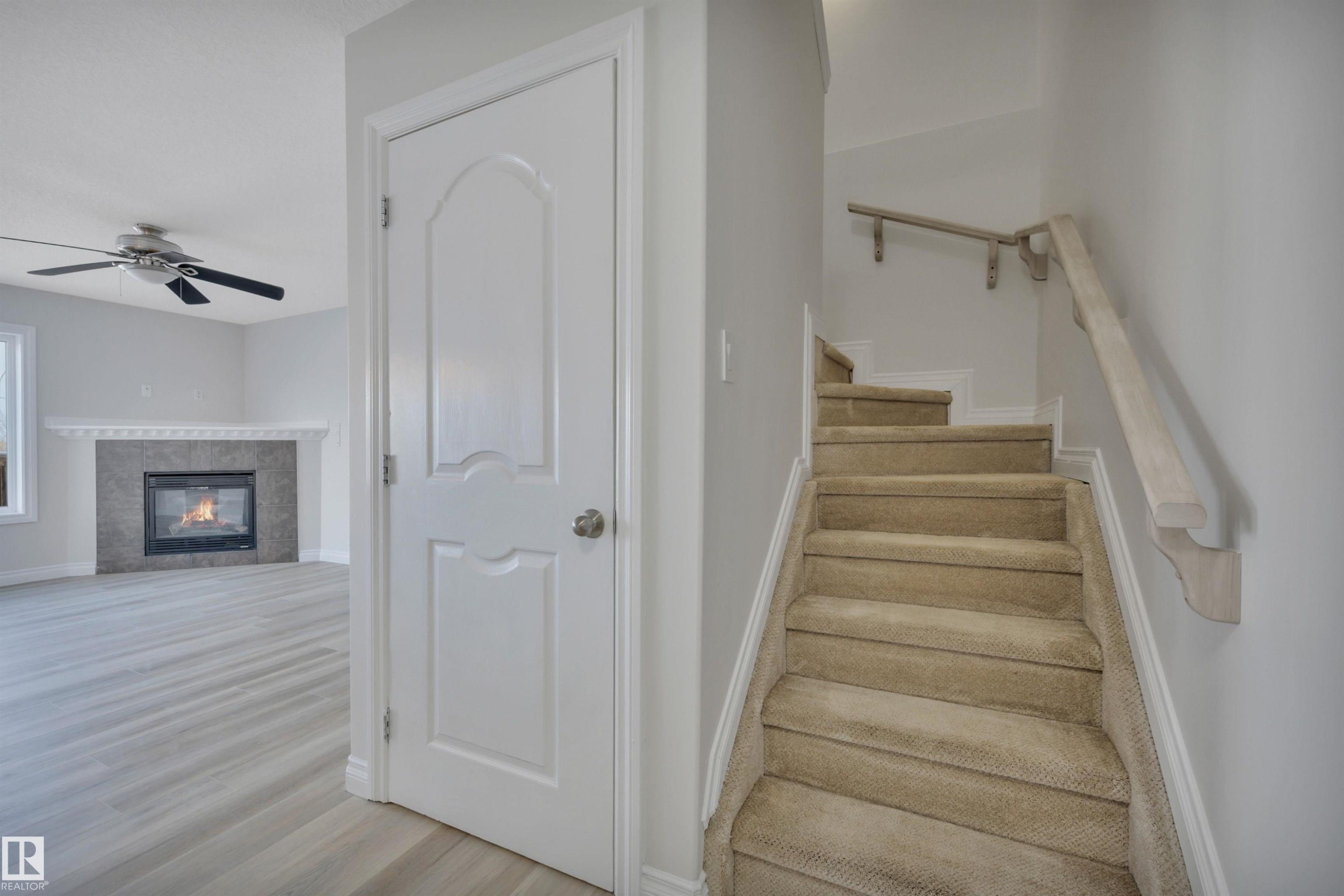 Stairway with a ceiling fan, a tile fireplace, and wood finished floors - 457 Aster Close, Leduc, AB - Indoor Photo Showing Other Room