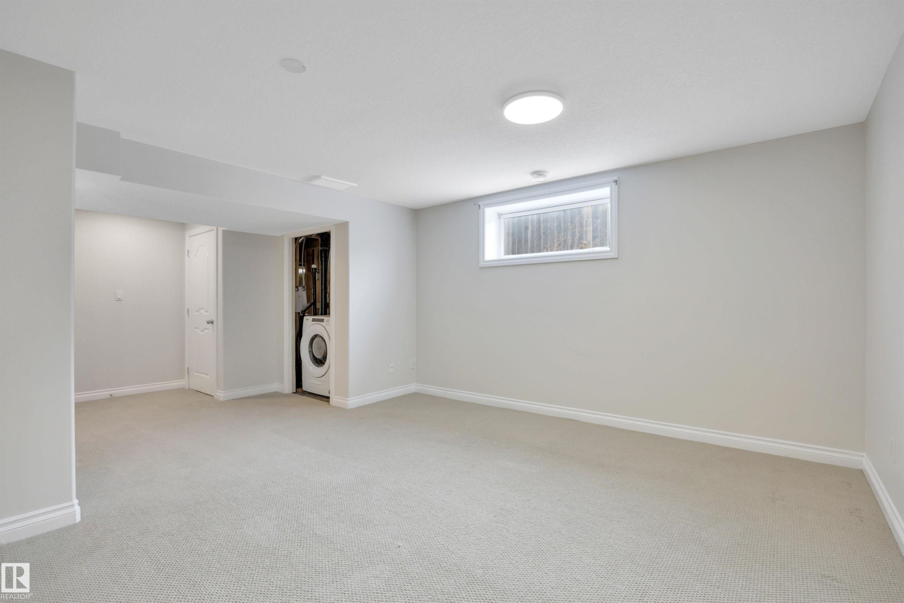 Below grade area with light colored carpet and washer / clothes dryer - 457 Aster Close, Leduc, AB - Indoor