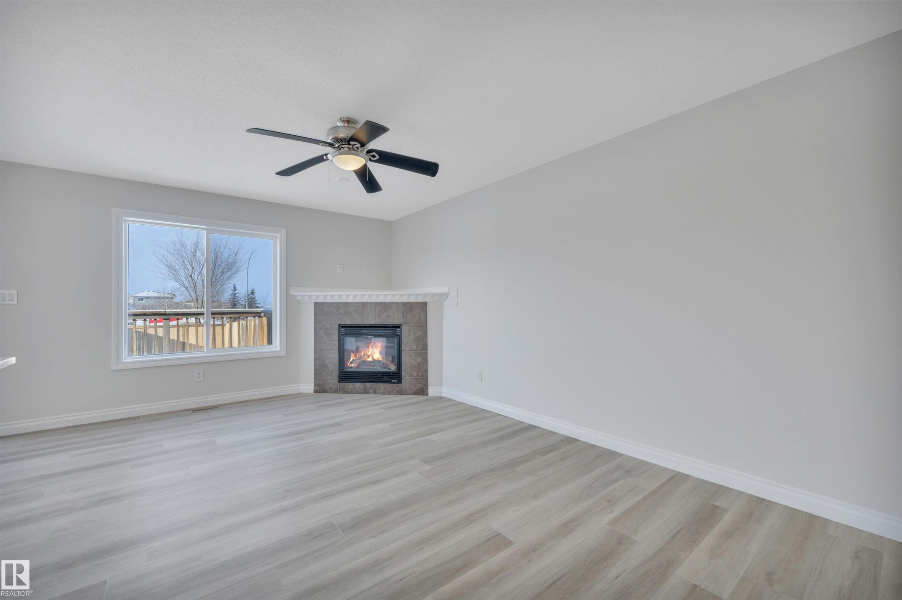 Unfurnished living room with a tiled fireplace, light wood-style flooring, and ceiling fan - 457 Aster Close, Leduc, AB - Indoor With Fireplace