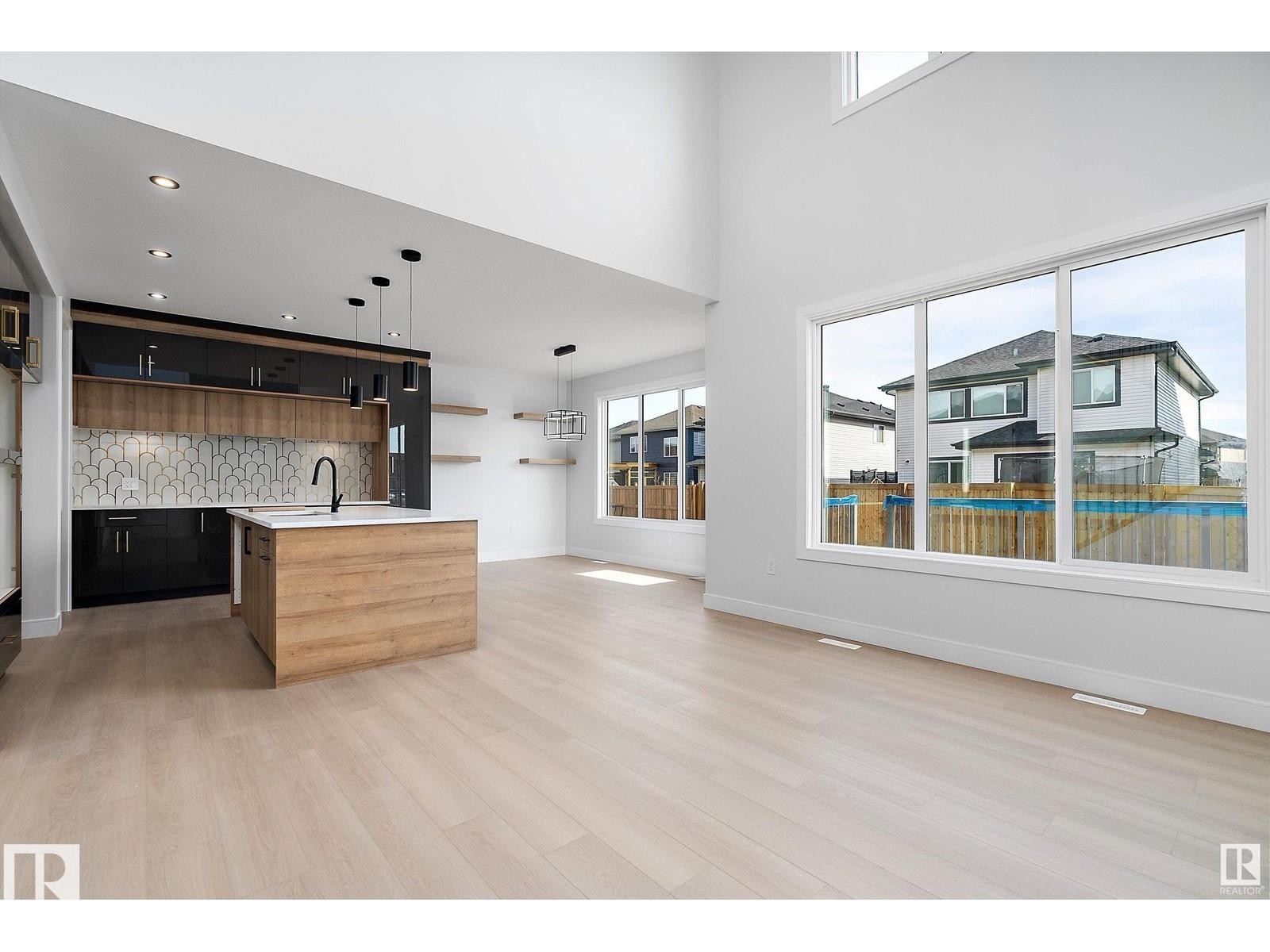 Kitchen featuring open shelves, a kitchen island with sink, open floor plan, healthy amount of natural light, and a towering ceiling - 138 South Ravines Drive, Devon, AB - Indoor Photo Showing Kitchen