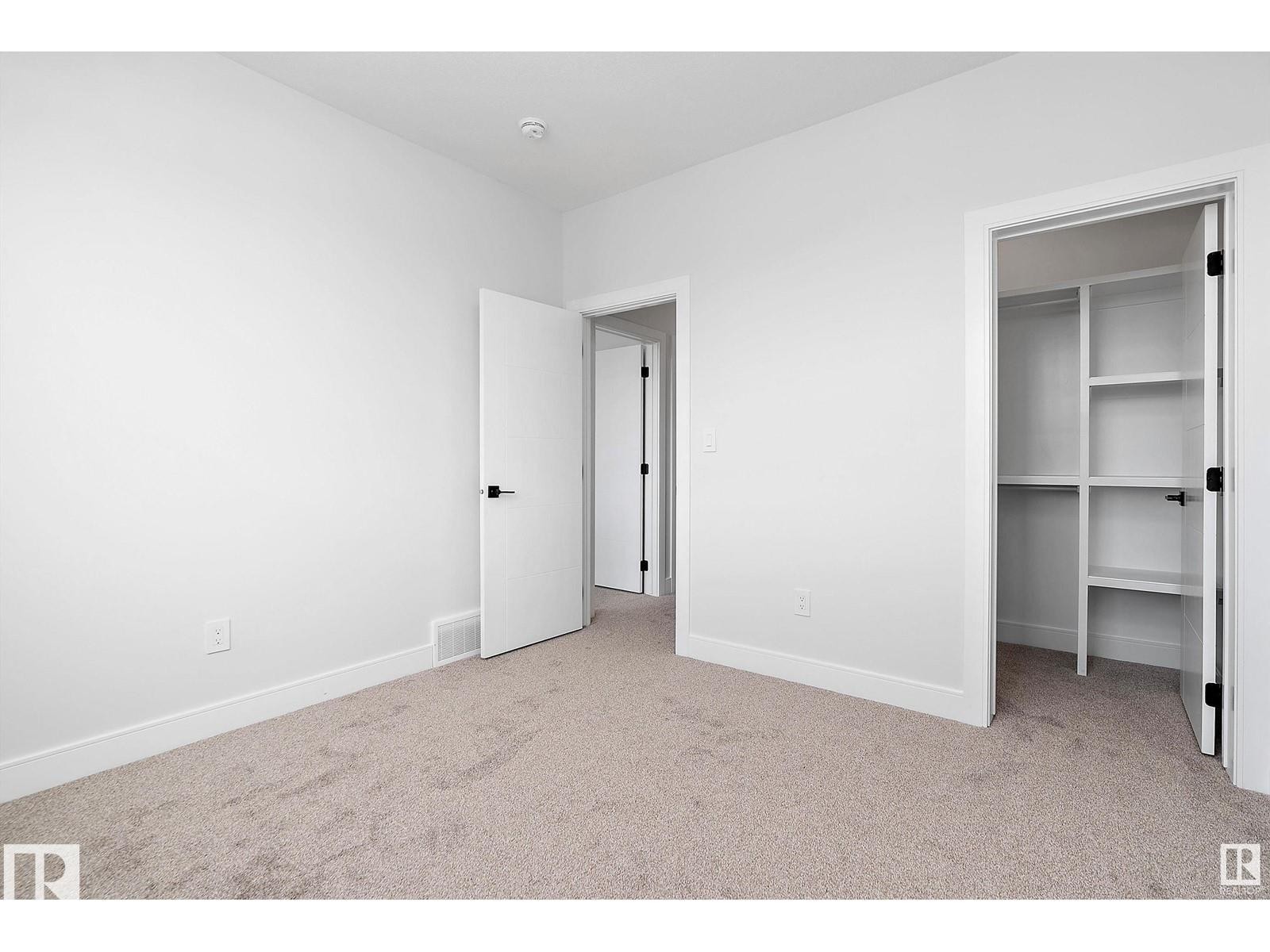 Unfurnished bedroom featuring a spacious closet and light colored carpet - 138 South Ravines Drive, Devon, AB - Indoor