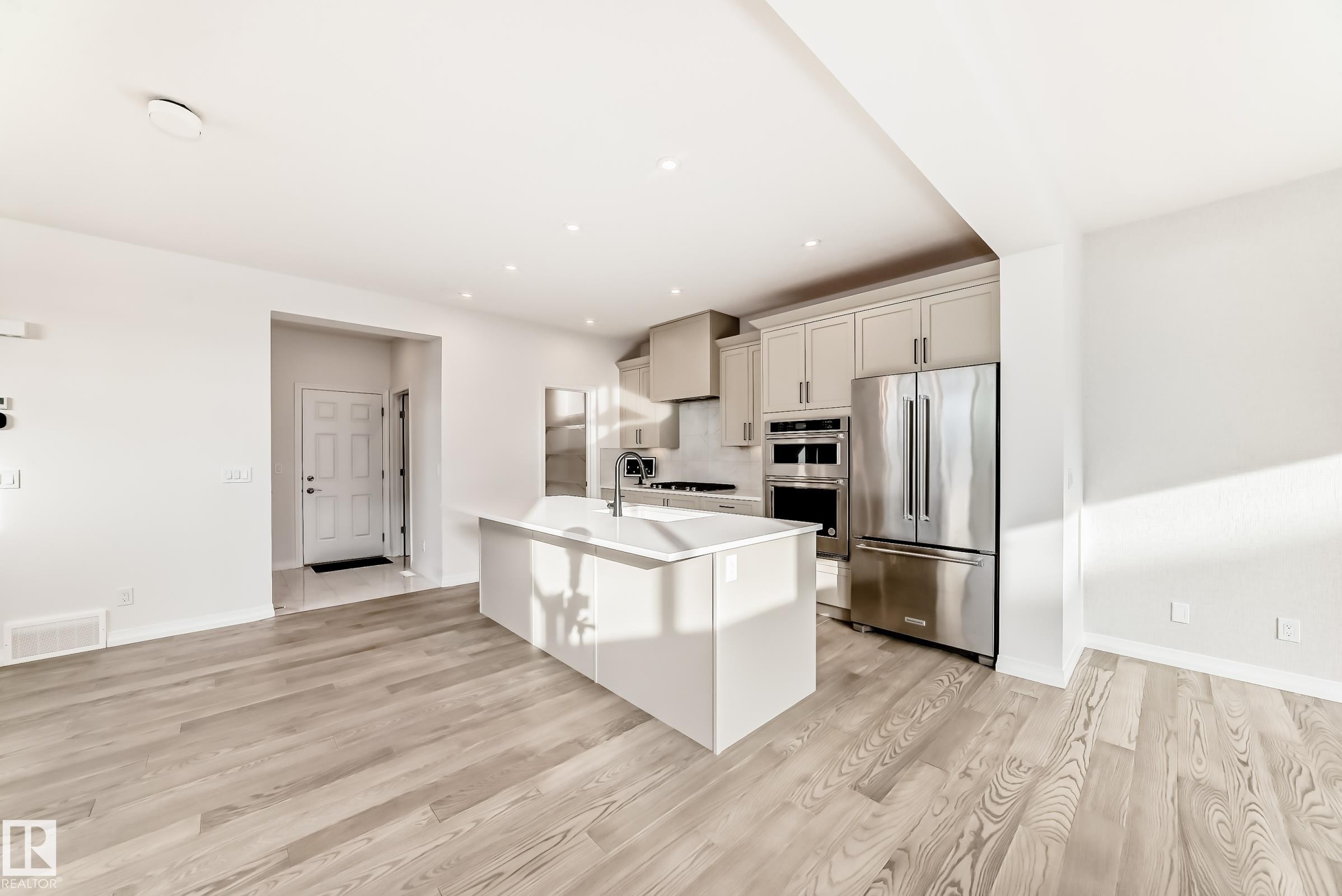 Kitchen with stainless steel appliances, a center island with sink, light wood-type flooring, a breakfast bar, and recessed lighting - 3249 Dixon Way, Edmonton, AB - Indoor Photo Showing Kitchen