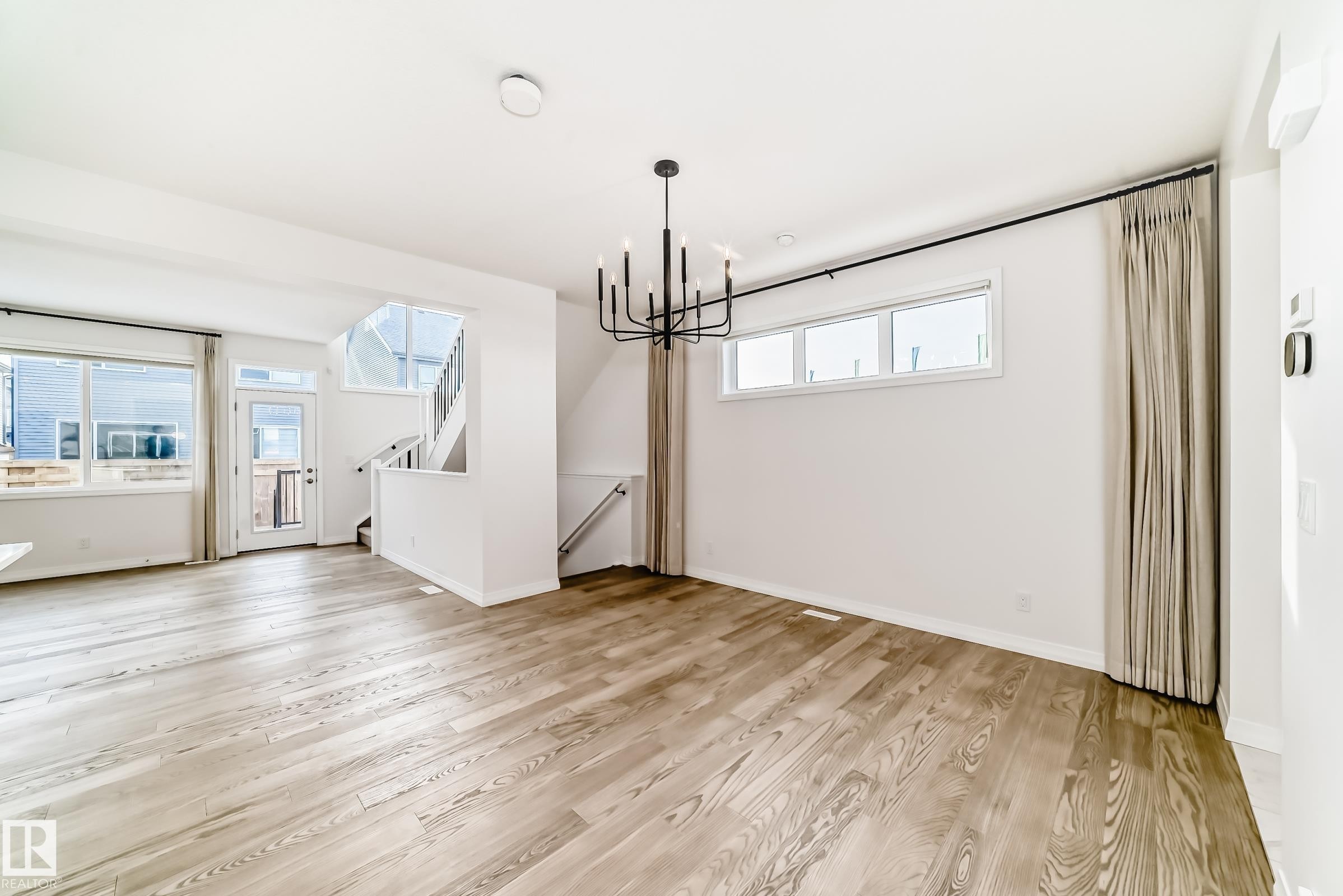 Unfurnished dining area with stairway, light wood-type flooring, and a chandelier - 3249 Dixon Way, Edmonton, AB - Indoor