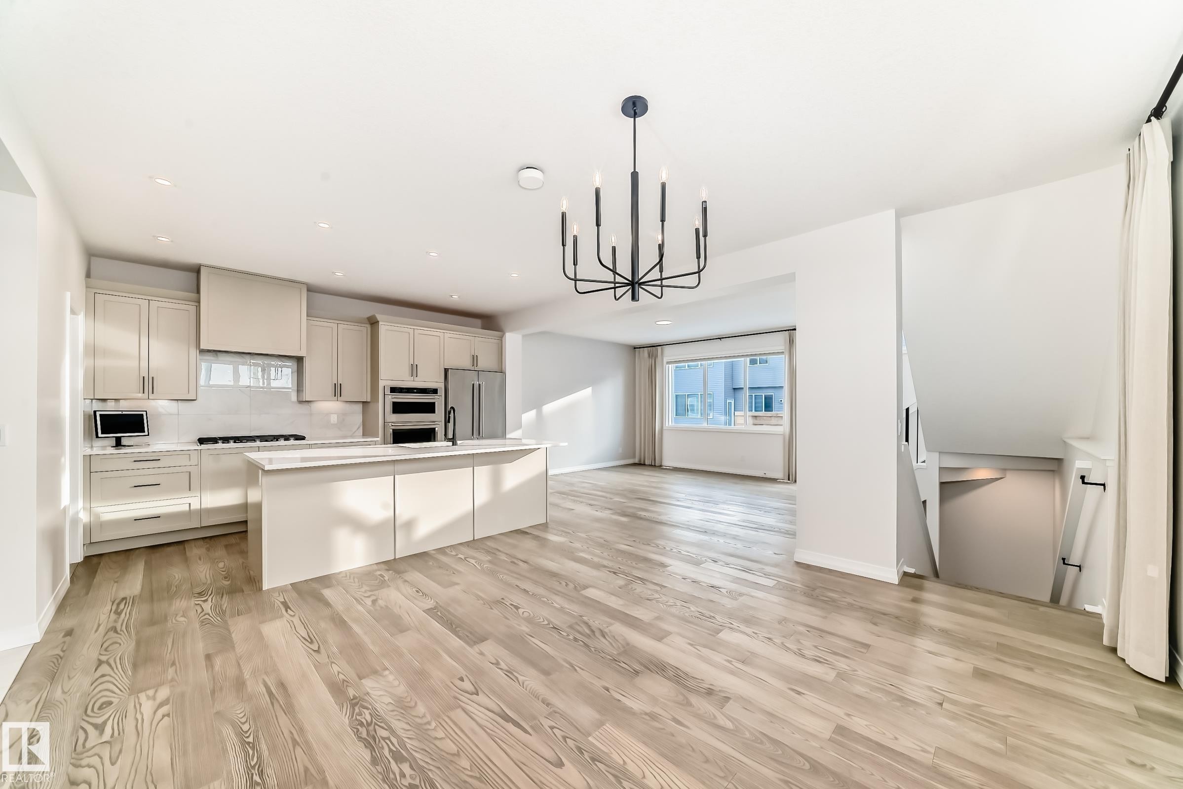 Kitchen featuring a chandelier, open floor plan, an island with sink, decorative light fixtures, and healthy amount of natural light - 3249 Dixon Way, Edmonton, AB - Indoor Photo Showing Kitchen With Upgraded Kitchen