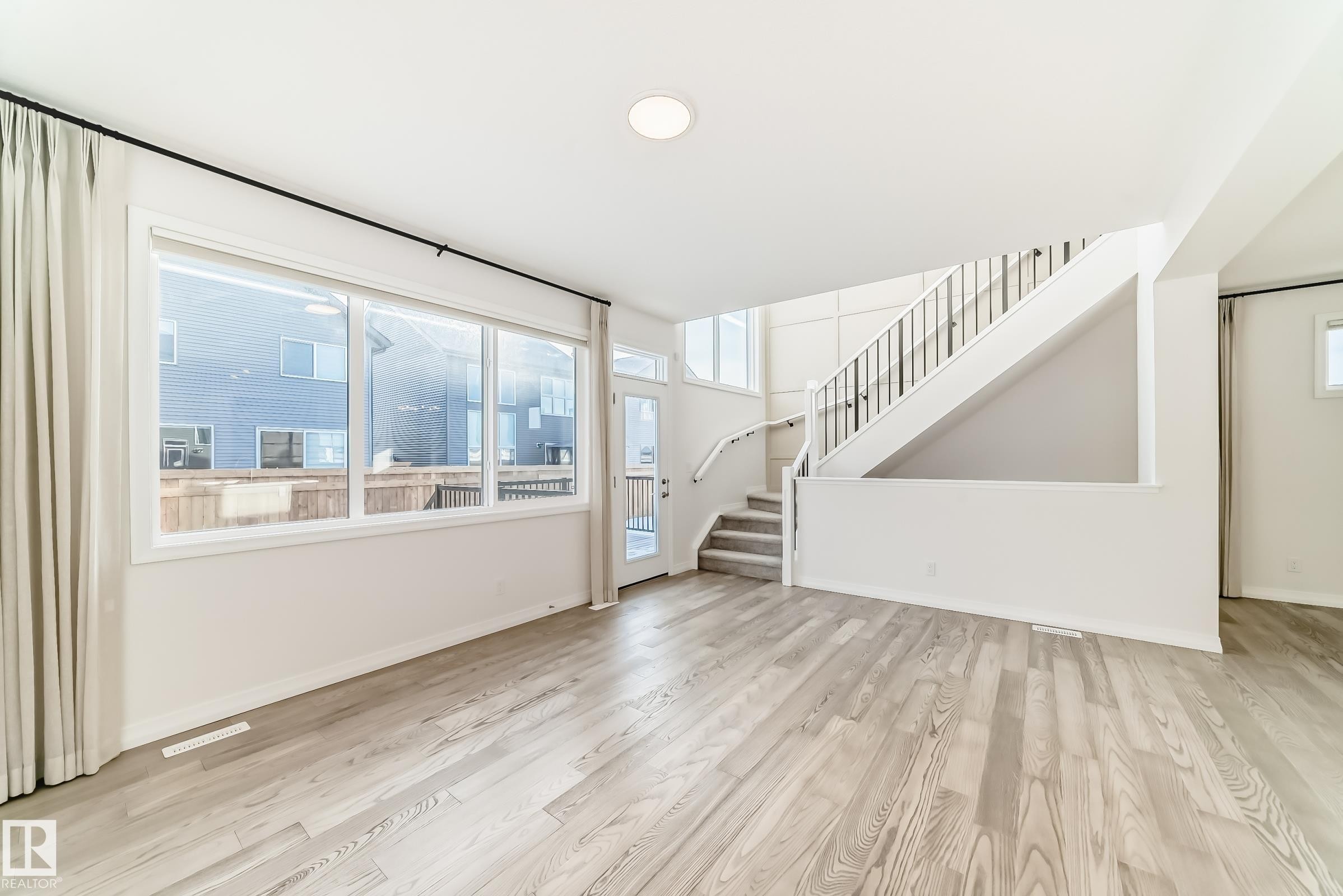 Unfurnished living room with stairway and light wood-style floors - 3249 Dixon Way, Edmonton, AB - Indoor Photo Showing Other Room