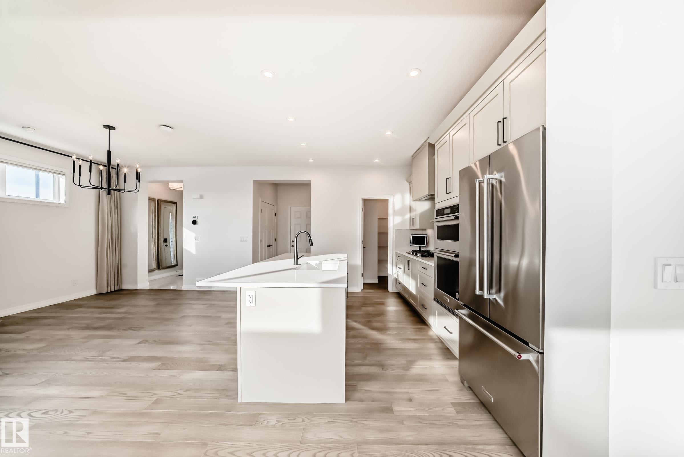 Kitchen featuring a center island with sink, stainless steel appliances, decorative light fixtures, light wood-style flooring, and recessed lighting - 3249 Dixon Way, Edmonton, AB - Indoor Photo Showing Kitchen With Upgraded Kitchen