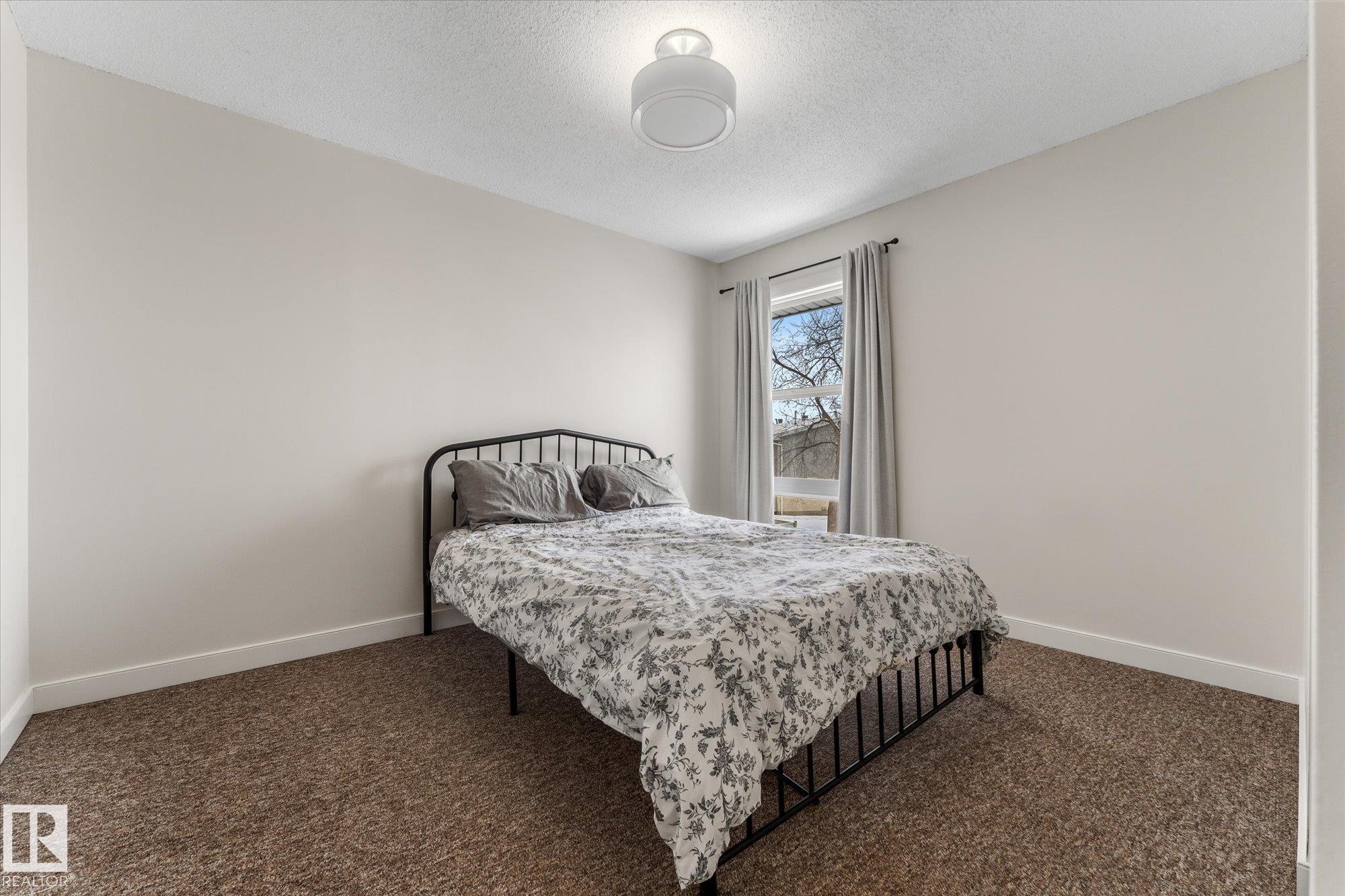 Carpeted bedroom with baseboards and a textured ceiling - 289 Grandin Village, St. Albert, AB - Indoor Photo Showing Bedroom