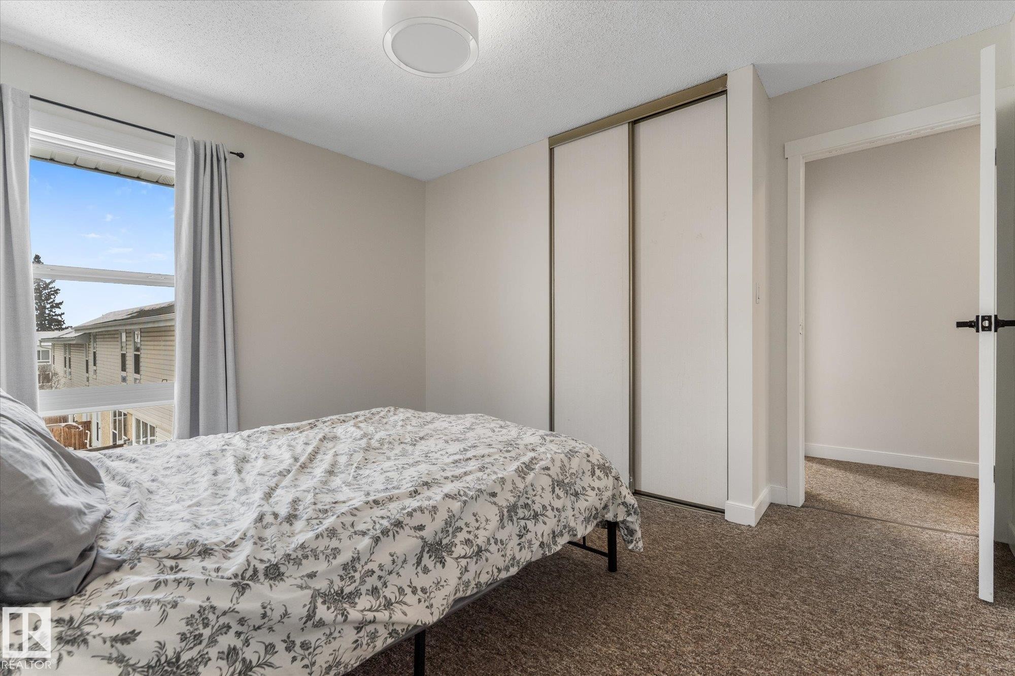 Carpeted bedroom with a textured ceiling and a closet - 289 Grandin Village, St. Albert, AB - Indoor Photo Showing Bedroom