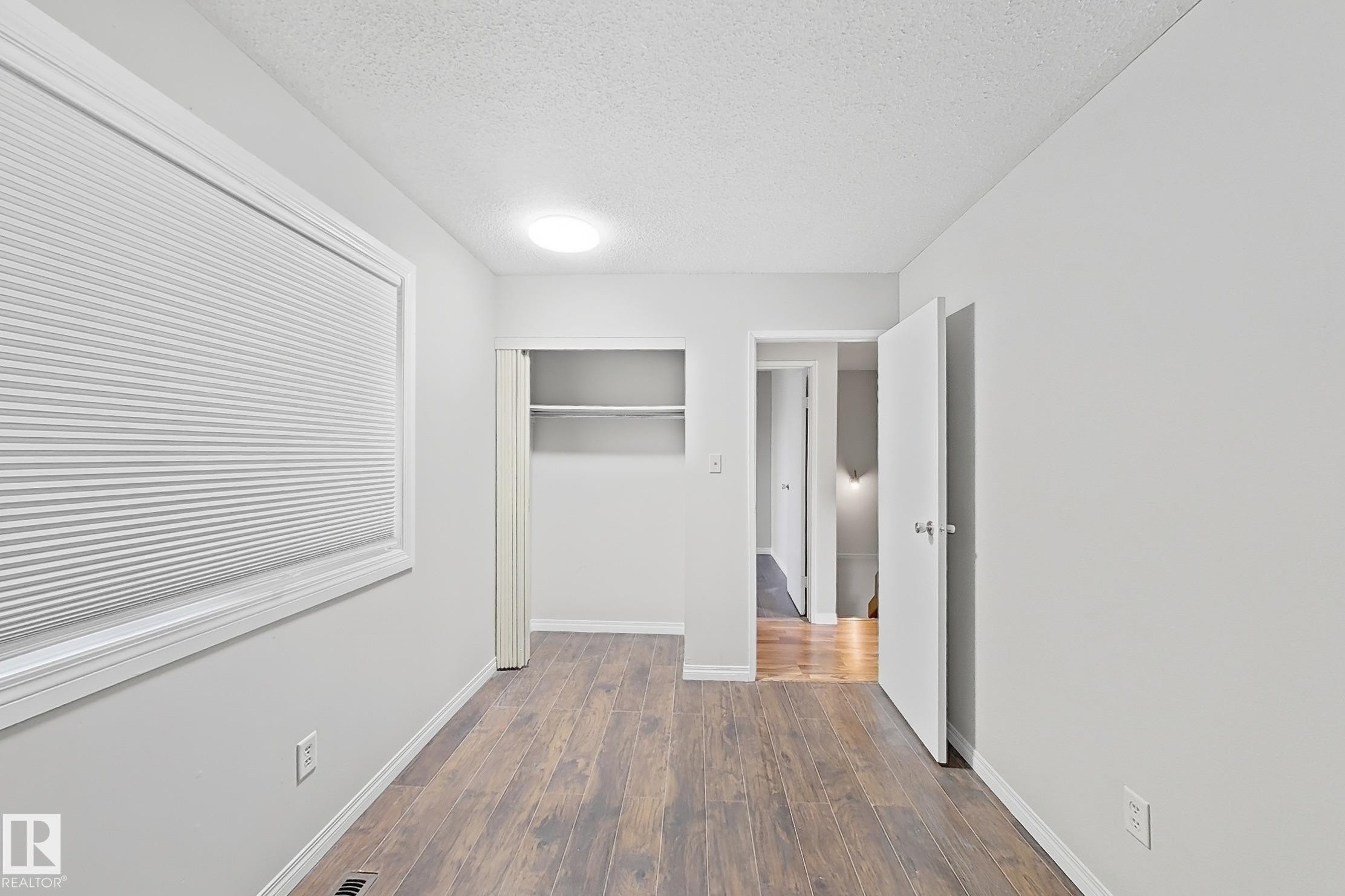 Unfurnished bedroom with a textured ceiling, dark wood-style floors, and a closet - 24 3812 20 Avenue, Edmonton, AB - Indoor Photo Showing Other Room