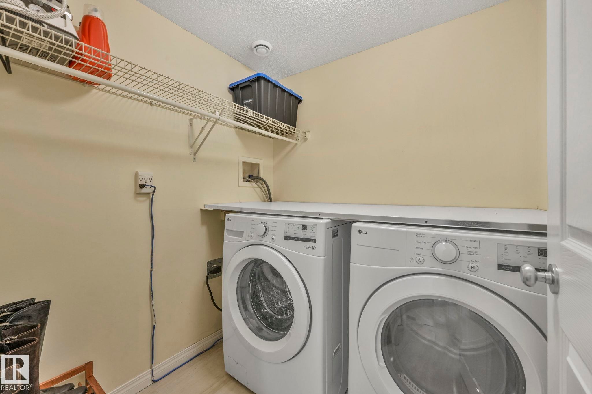 Washroom with a textured ceiling and washing machine and clothes dryer - 23 4755 Terwillegar Common, Edmonton, AB - Indoor Photo Showing Laundry Room