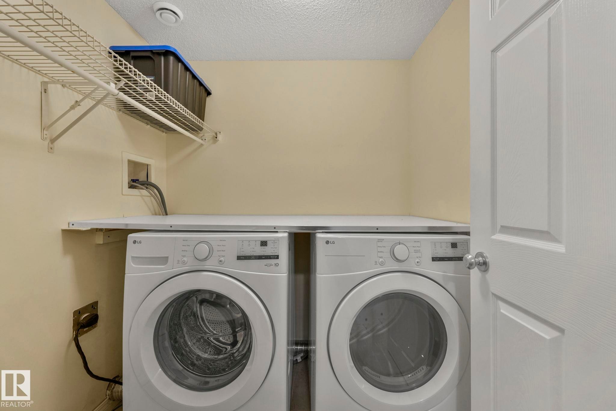 Washroom with a textured ceiling and washing machine and dryer - 23 4755 Terwillegar Common, Edmonton, AB - Indoor Photo Showing Laundry Room