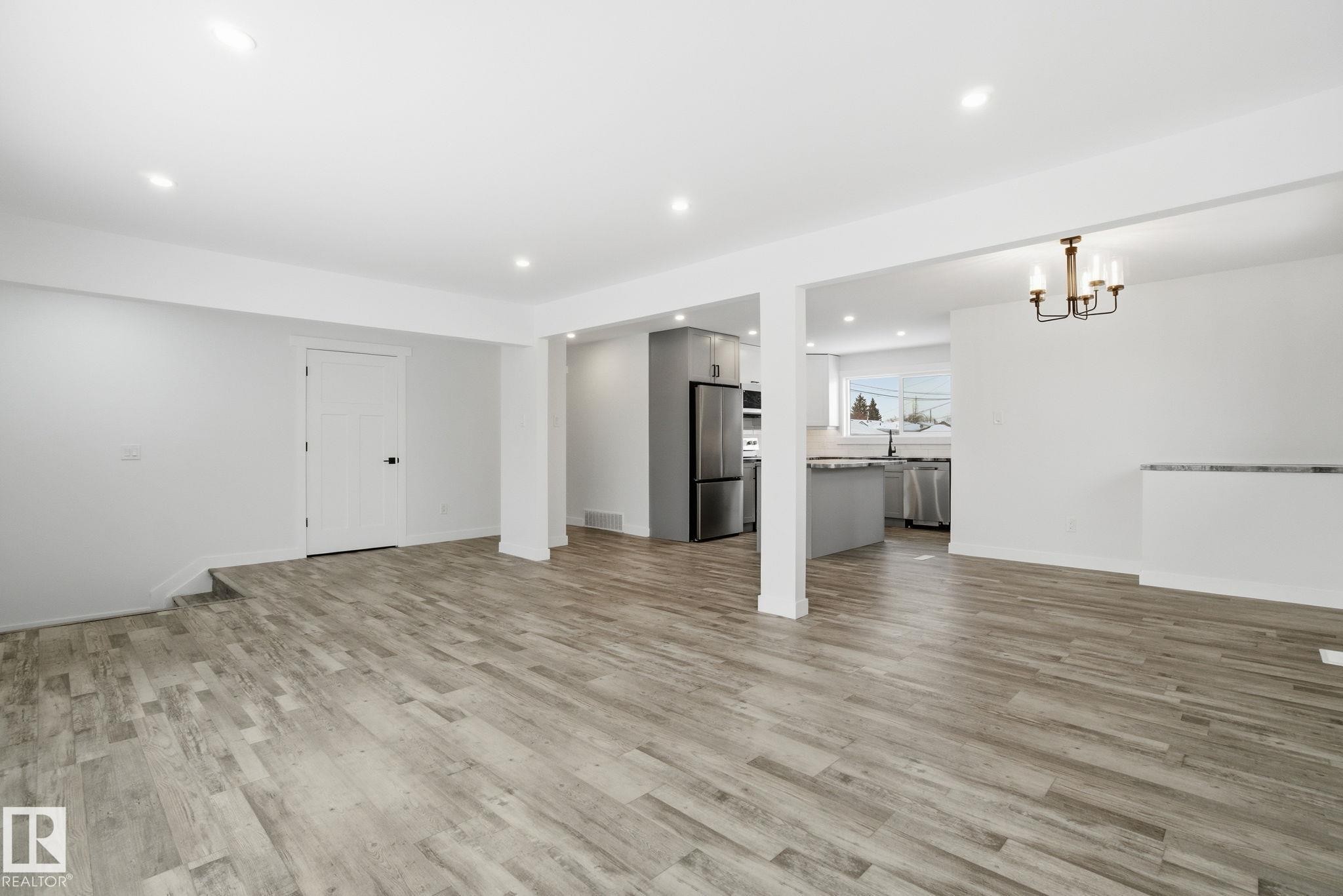 Unfurnished living room with recessed lighting, light wood-type flooring, and a chandelier - 7112 132 Avenue, Edmonton, AB - Indoor