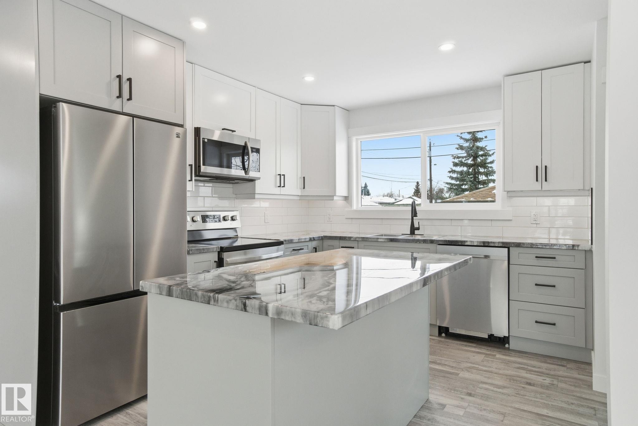 Kitchen with stainless steel appliances, a center island, light stone counters, light wood-style floors, and recessed lighting - 7112 132 Avenue, Edmonton, AB - Indoor Photo Showing Kitchen With Upgraded Kitchen