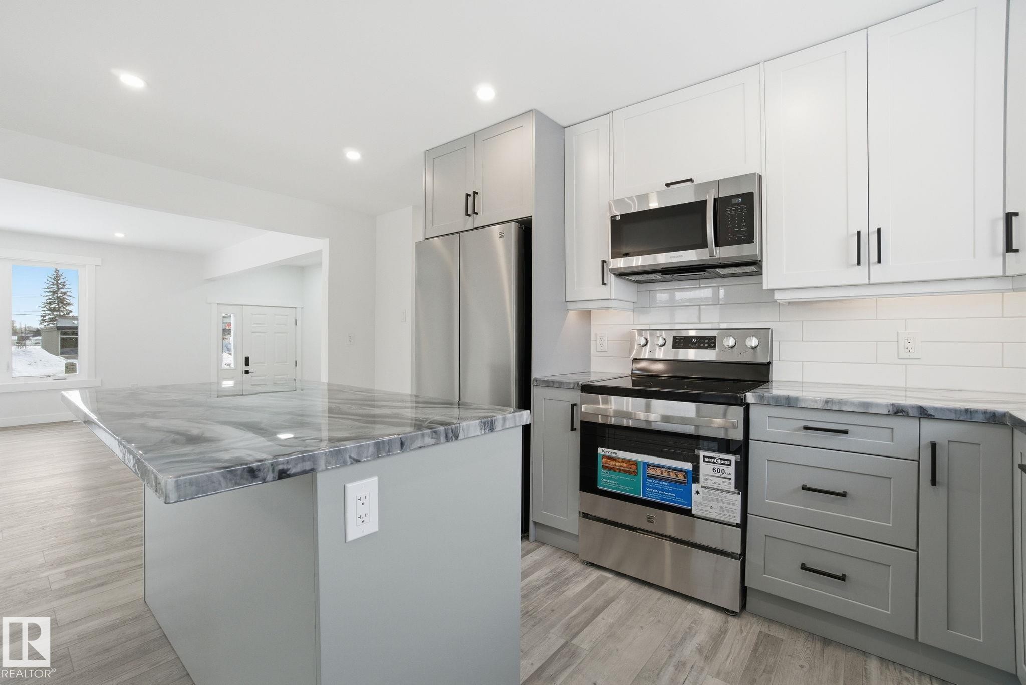 Kitchen with gray cabinetry, stainless steel appliances, light wood-style flooring, recessed lighting, and a center island - 7112 132 Avenue, Edmonton, AB - Indoor Photo Showing Kitchen With Upgraded Kitchen