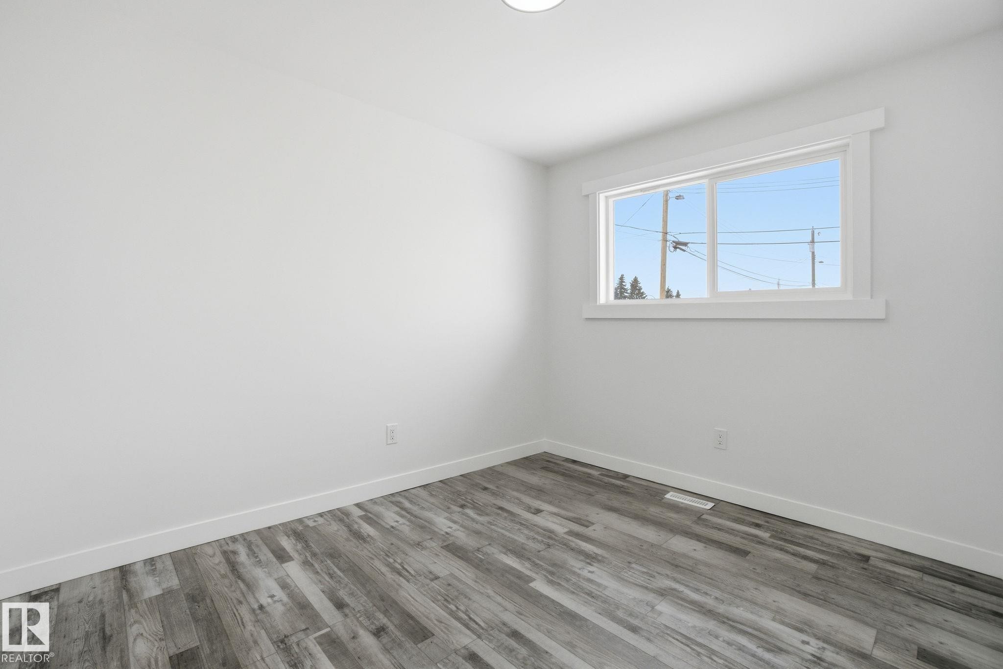 Unfurnished room featuring wood finished floors and baseboards - 7112 132 Avenue, Edmonton, AB - Indoor Photo Showing Other Room