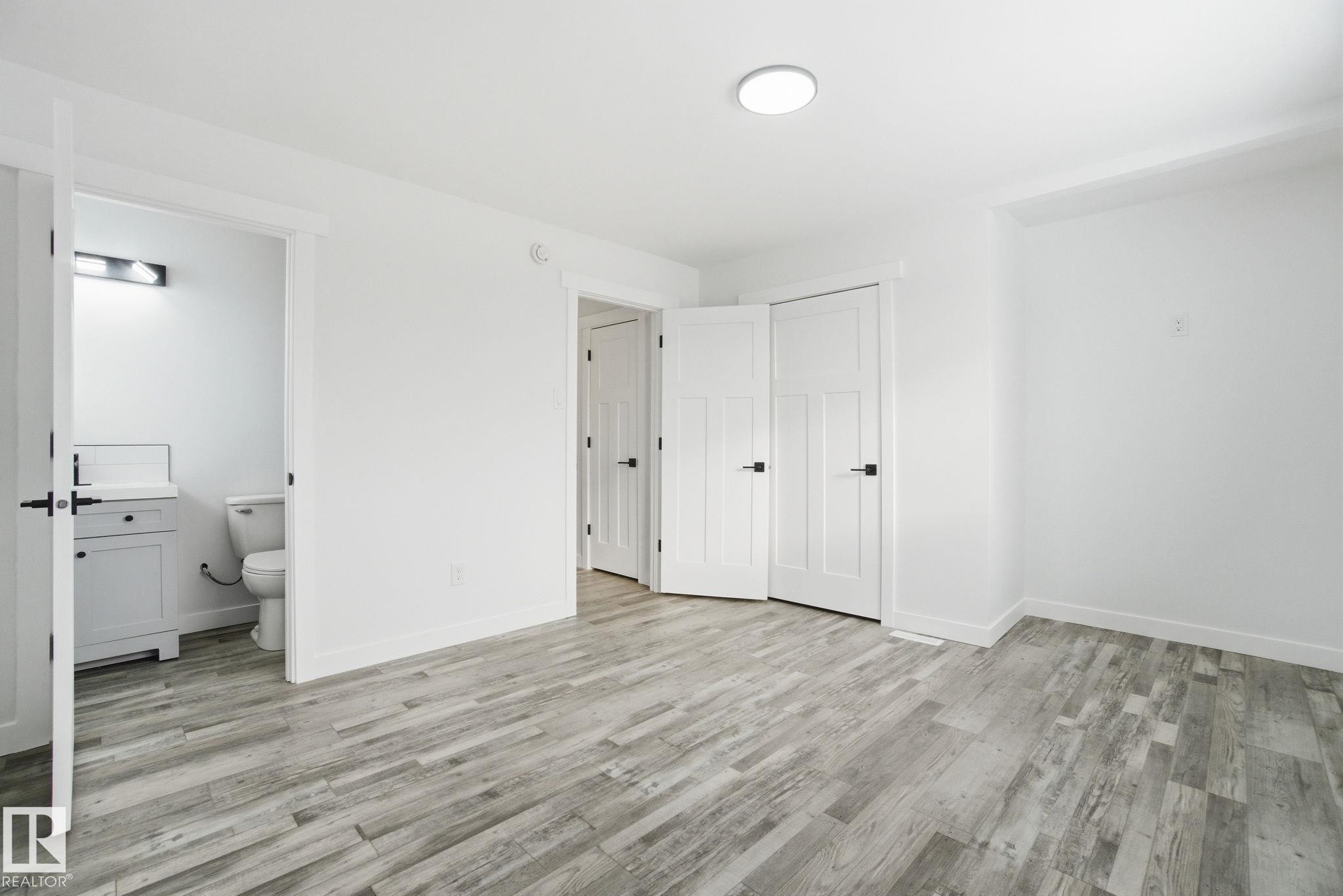 Unfurnished bedroom with a closet, light wood-style flooring, and ensuite bathroom - 7112 132 Avenue, Edmonton, AB - Indoor Photo Showing Other Room