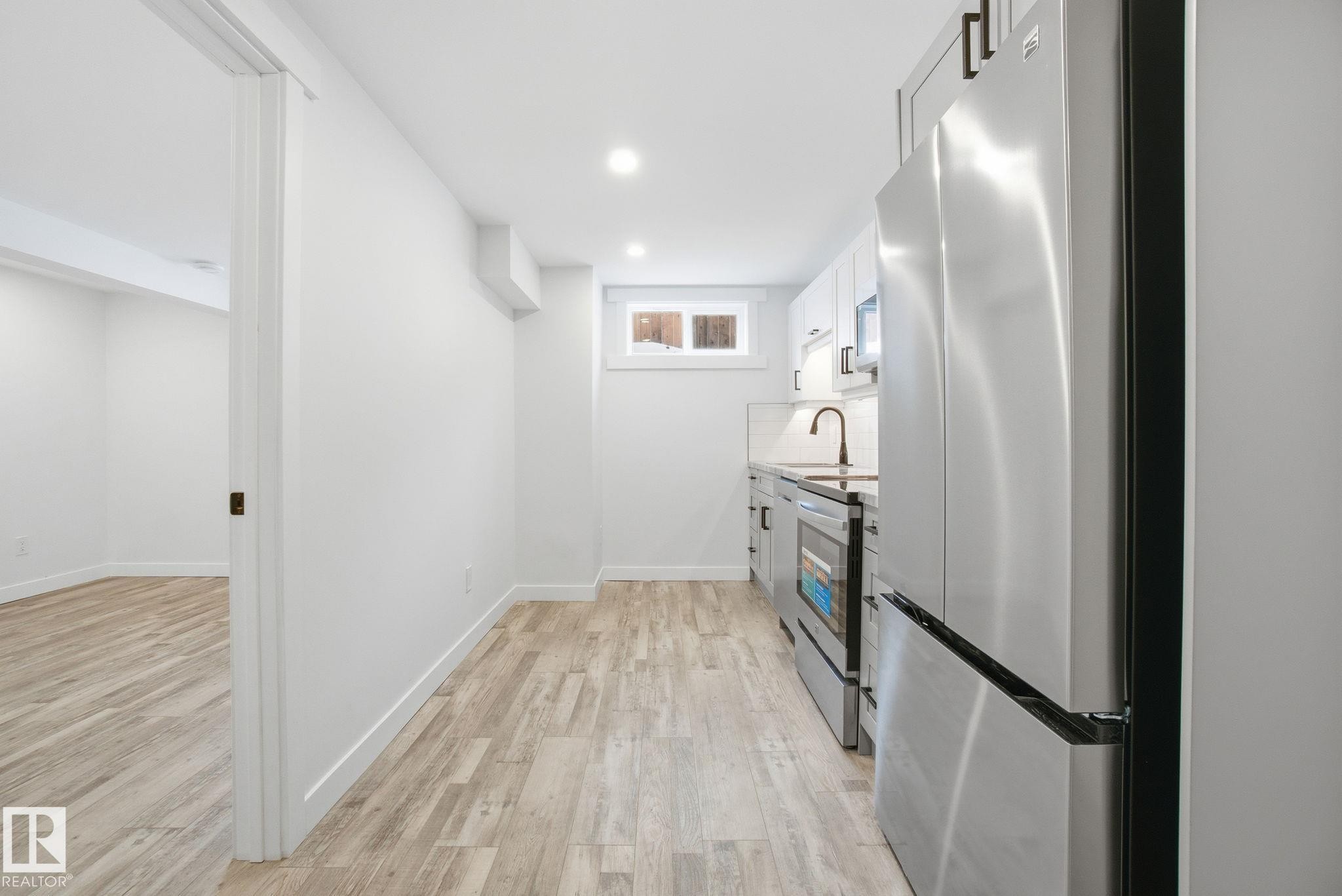 Kitchen with appliances with stainless steel finishes, light wood finished floors, white cabinetry, recessed lighting, and tasteful backsplash - 7112 132 Avenue, Edmonton, AB - Indoor Photo Showing Kitchen