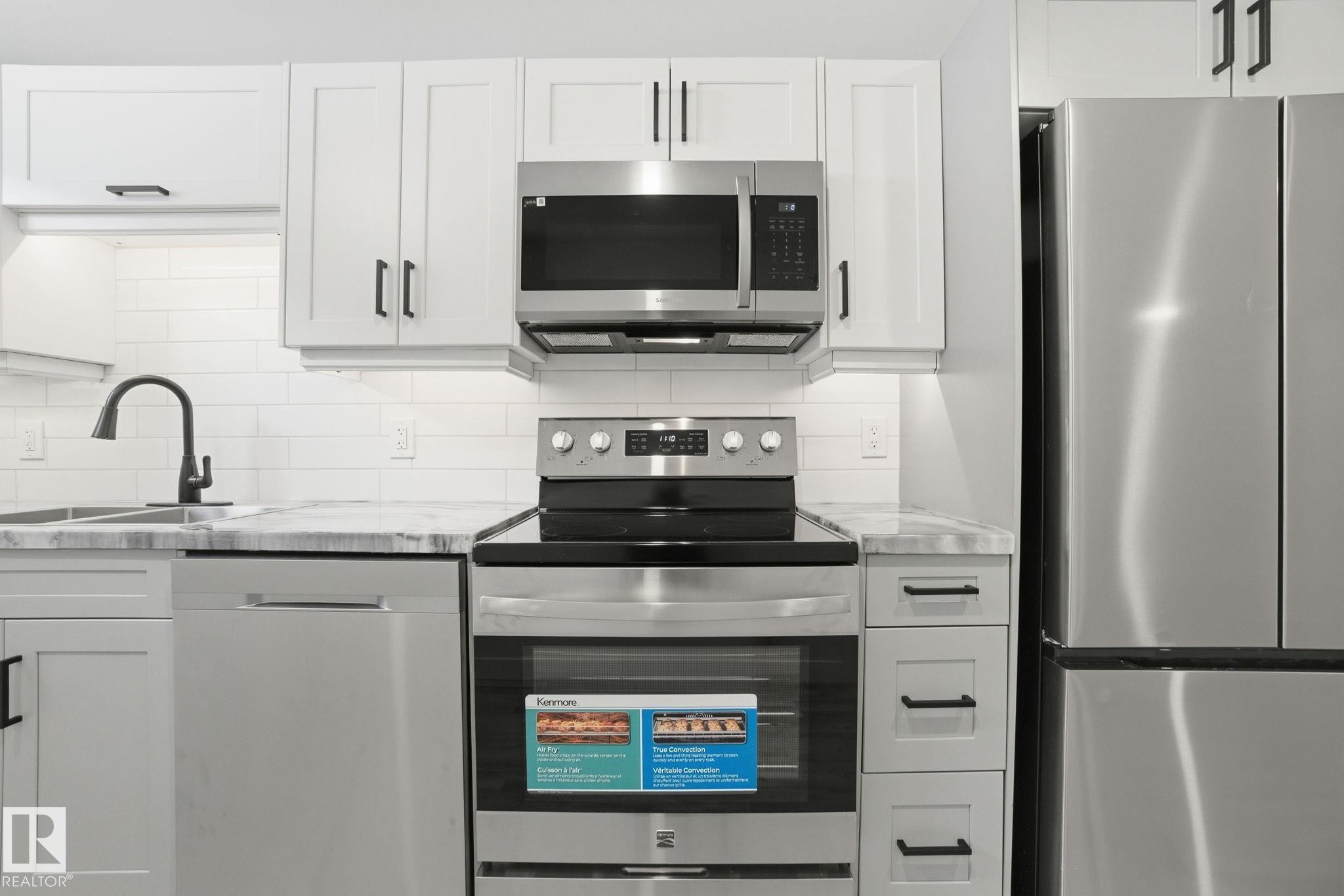Kitchen featuring stainless steel appliances, tasteful backsplash, and white cabinets - 7112 132 Avenue, Edmonton, AB - Indoor Photo Showing Kitchen With Upgraded Kitchen