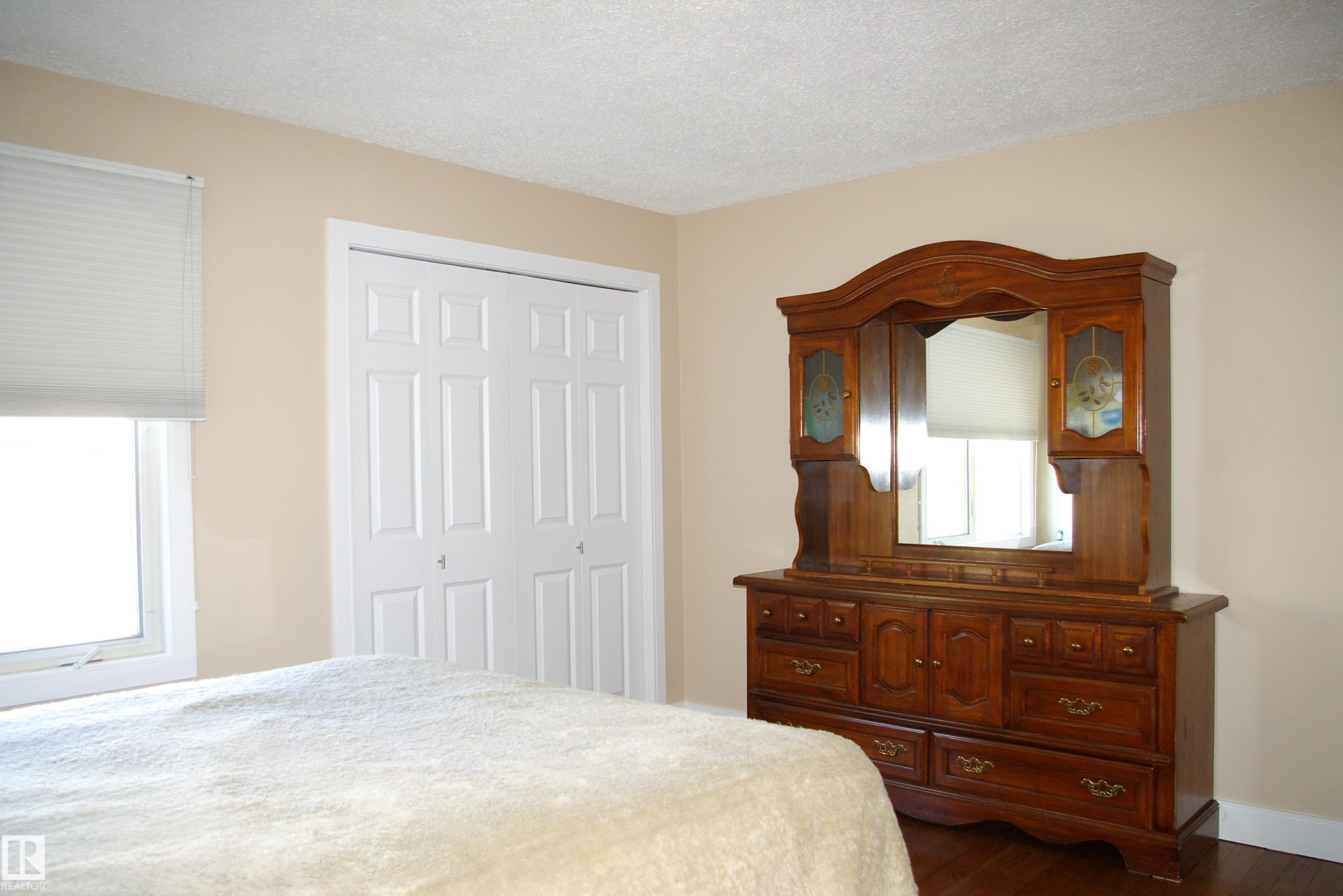 Bedroom with a textured ceiling, a closet, dark wood-style floors, and multiple windows - 168 Warwick Road, Edmonton, AB - Indoor Photo Showing Bedroom