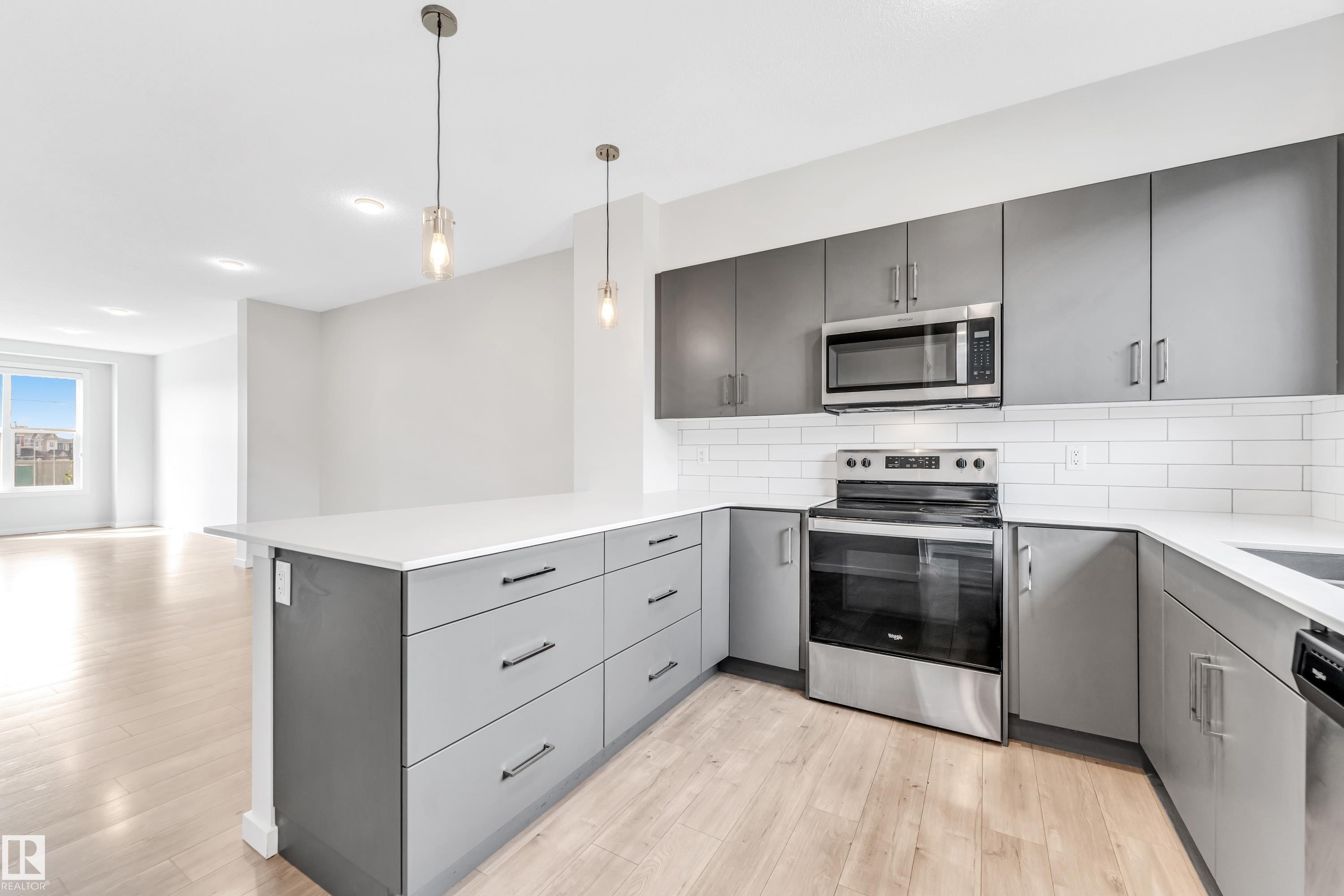 Kitchen featuring gray cabinets, appliances with stainless steel finishes, a peninsula, light wood-style floors, and pendant lighting - 2095 Maple Road, Edmonton, AB - Indoor Photo Showing Kitchen With Upgraded Kitchen