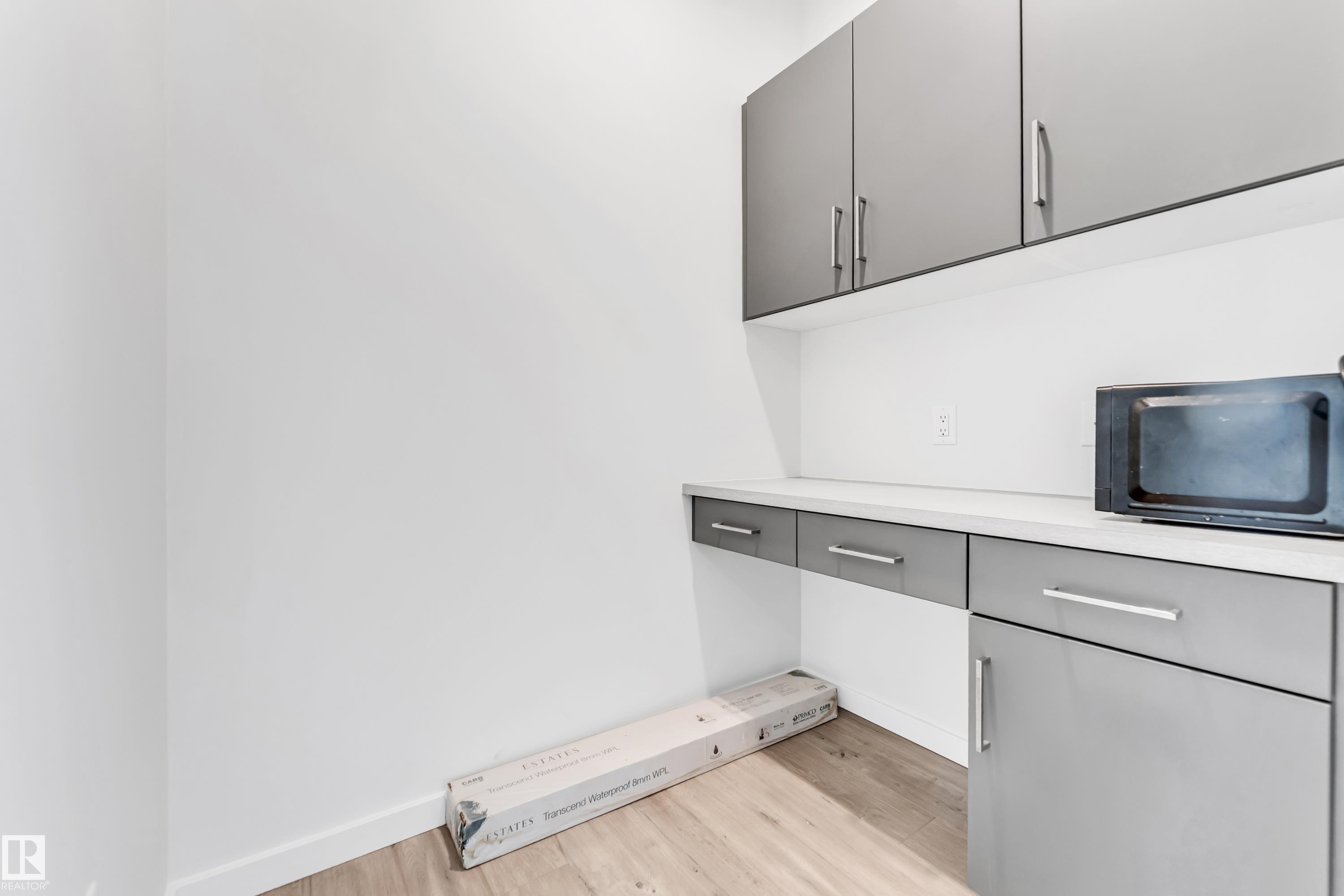 Detailed view of wood finished floors and black microwave - 2095 Maple Road, Edmonton, AB - Indoor Photo Showing Other Room
