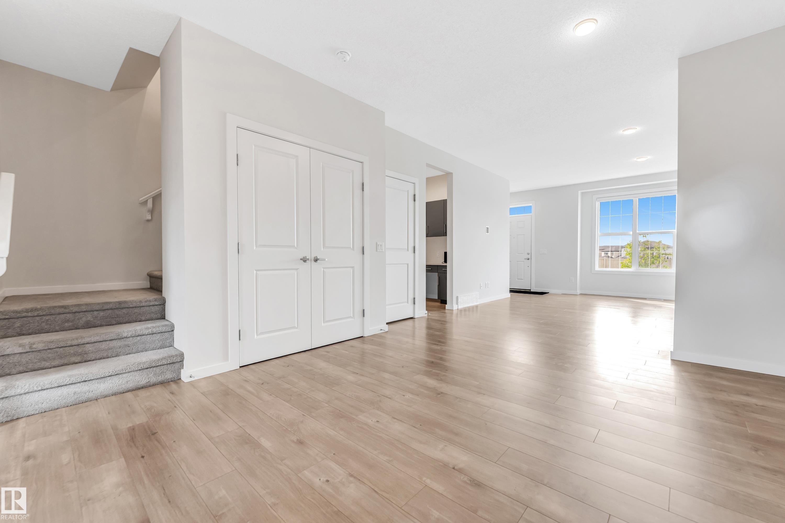 Unfurnished living room with light wood-type flooring and stairway - 2095 Maple Road, Edmonton, AB - Indoor Photo Showing Other Room