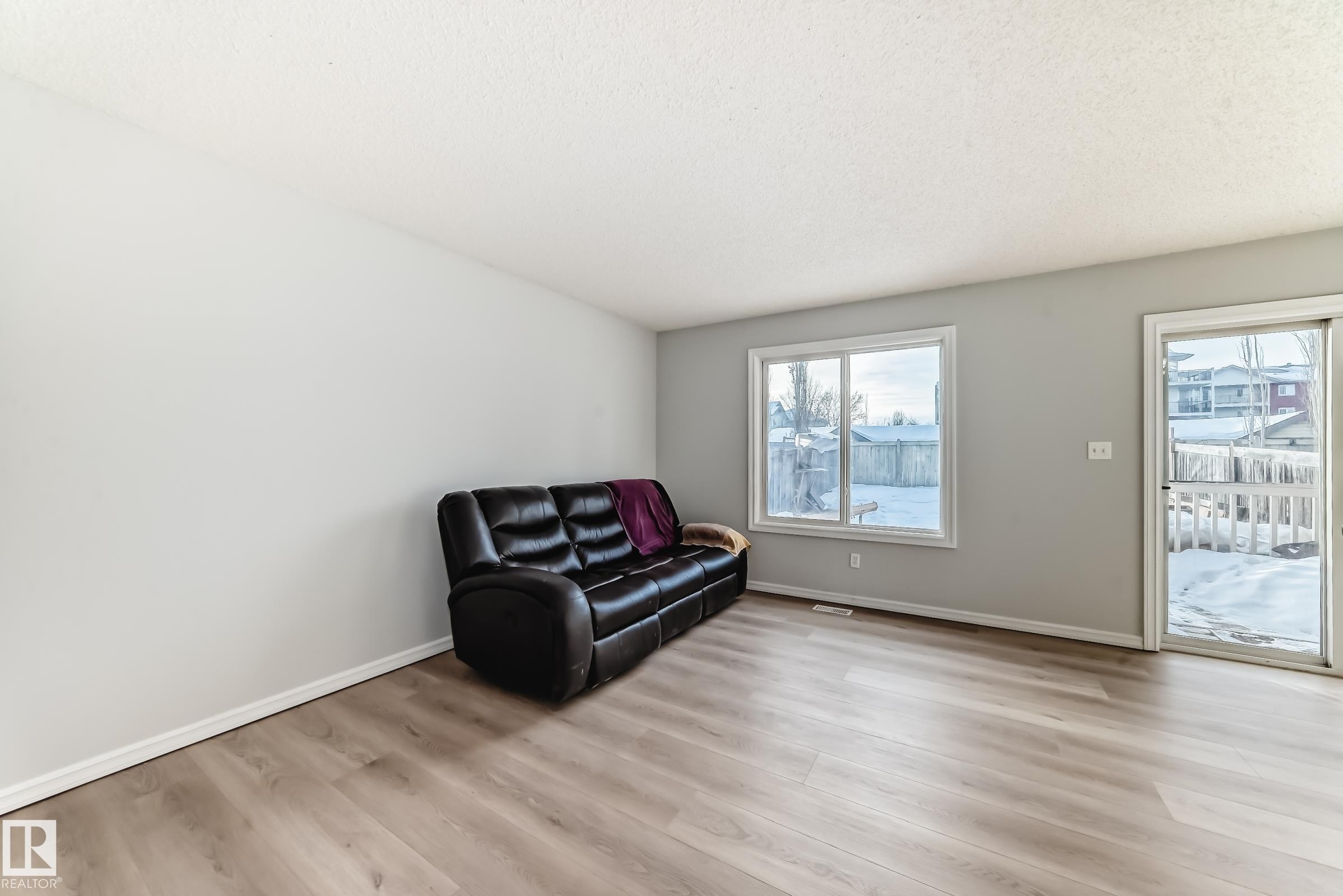 Sitting room featuring light wood-type flooring and a textured ceiling - 7731 8 Avenue, Edmonton, AB - Indoor Photo Showing Living Room