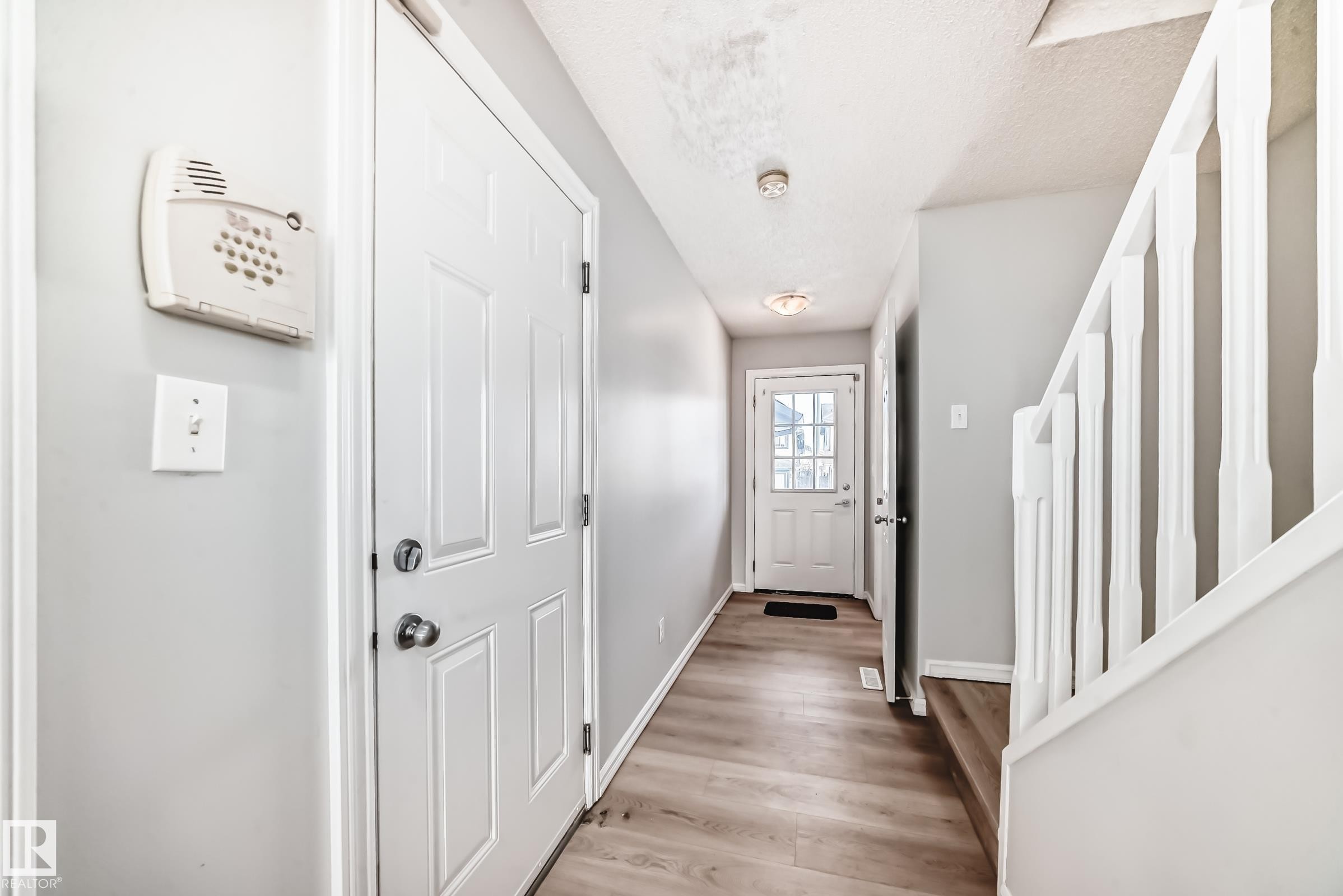 Doorway to outside with wood finished floors and a textured ceiling - 7731 8 Avenue, Edmonton, AB - Indoor Photo Showing Other Room