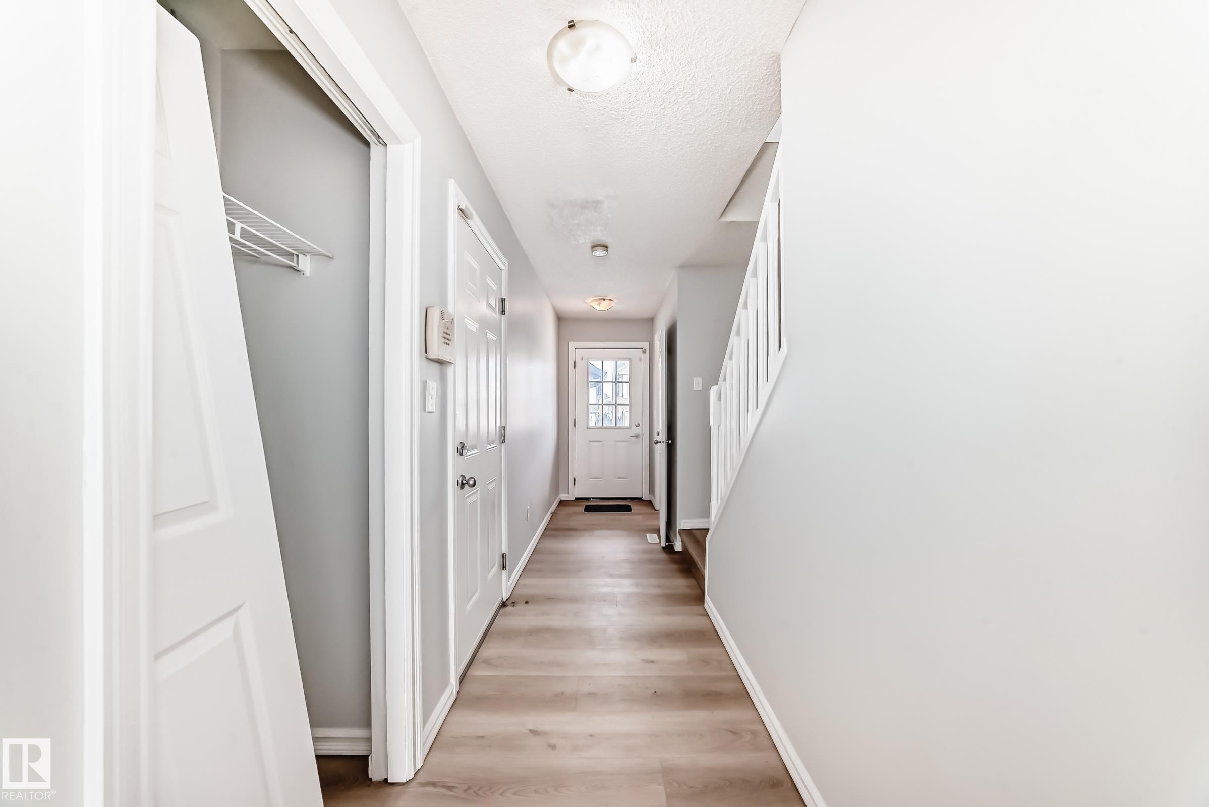 Corridor with stairway, light wood-style floors, and a textured ceiling - 7731 8 Avenue, Edmonton, AB - Indoor Photo Showing Other Room