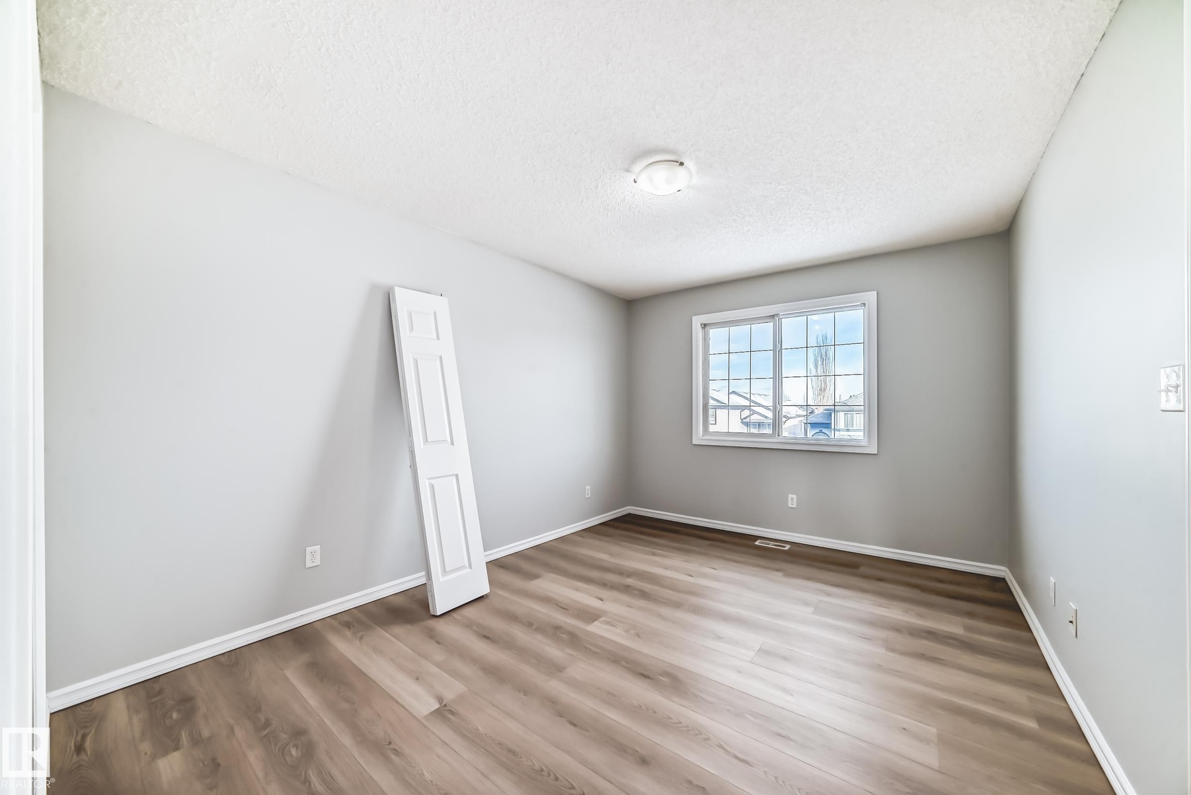 Empty room featuring light wood-style floors and a textured ceiling - 7731 8 Avenue, Edmonton, AB - Indoor Photo Showing Other Room