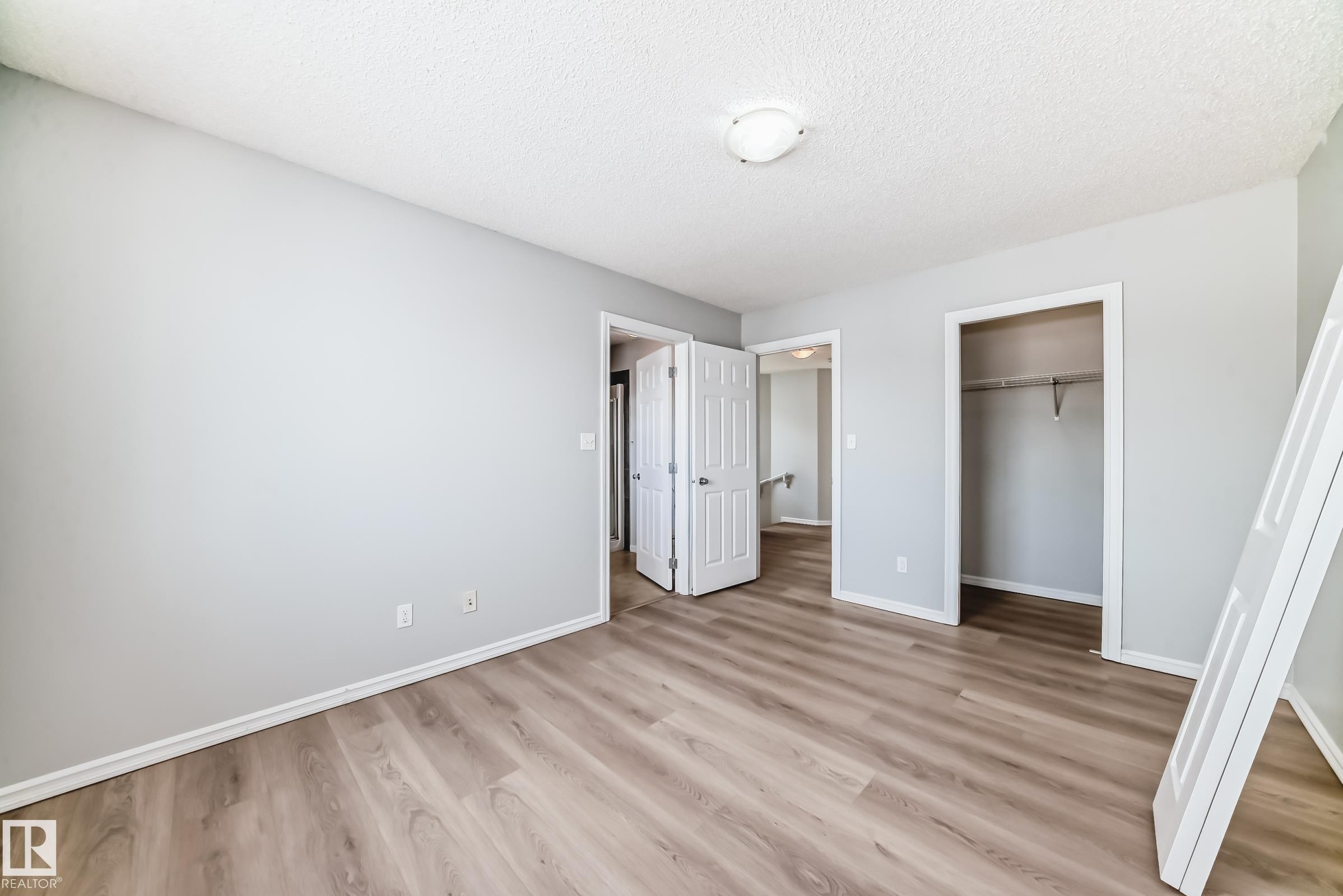 Unfurnished bedroom with light wood-style flooring, a closet, and a textured ceiling - 7731 8 Avenue, Edmonton, AB - Indoor Photo Showing Other Room