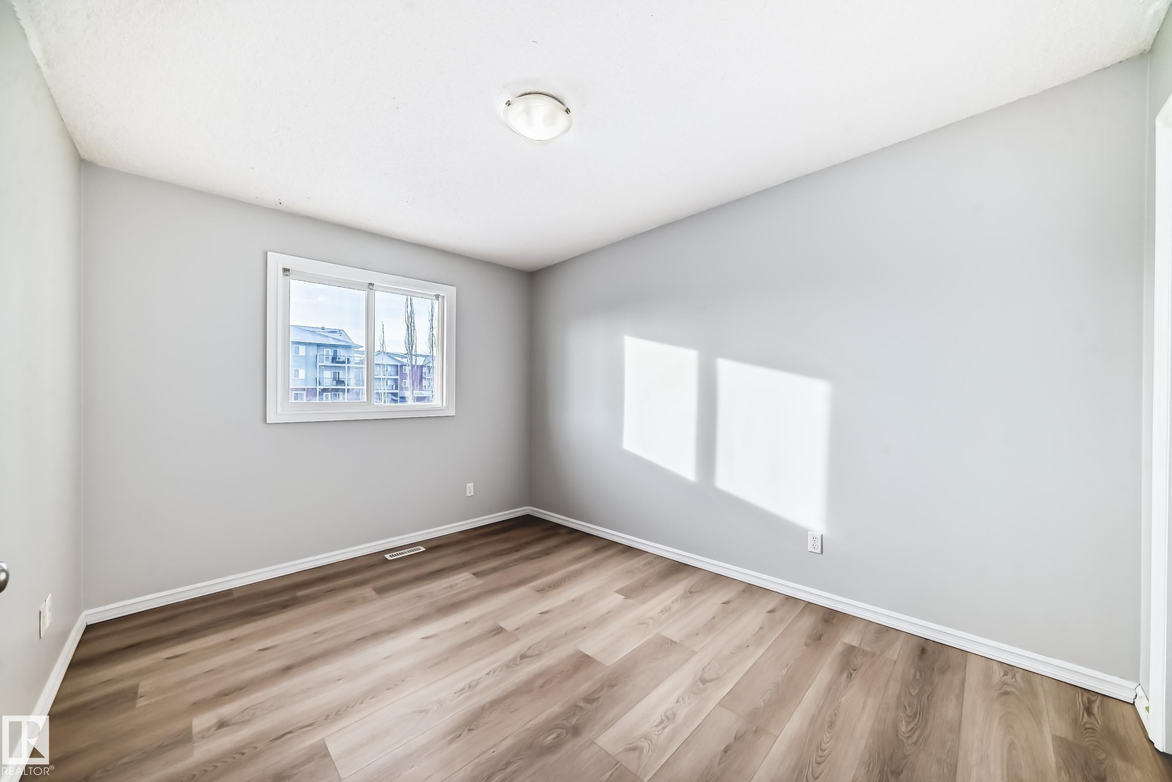 Spare room with light wood-style flooring and baseboards - 7731 8 Avenue, Edmonton, AB - Indoor Photo Showing Other Room