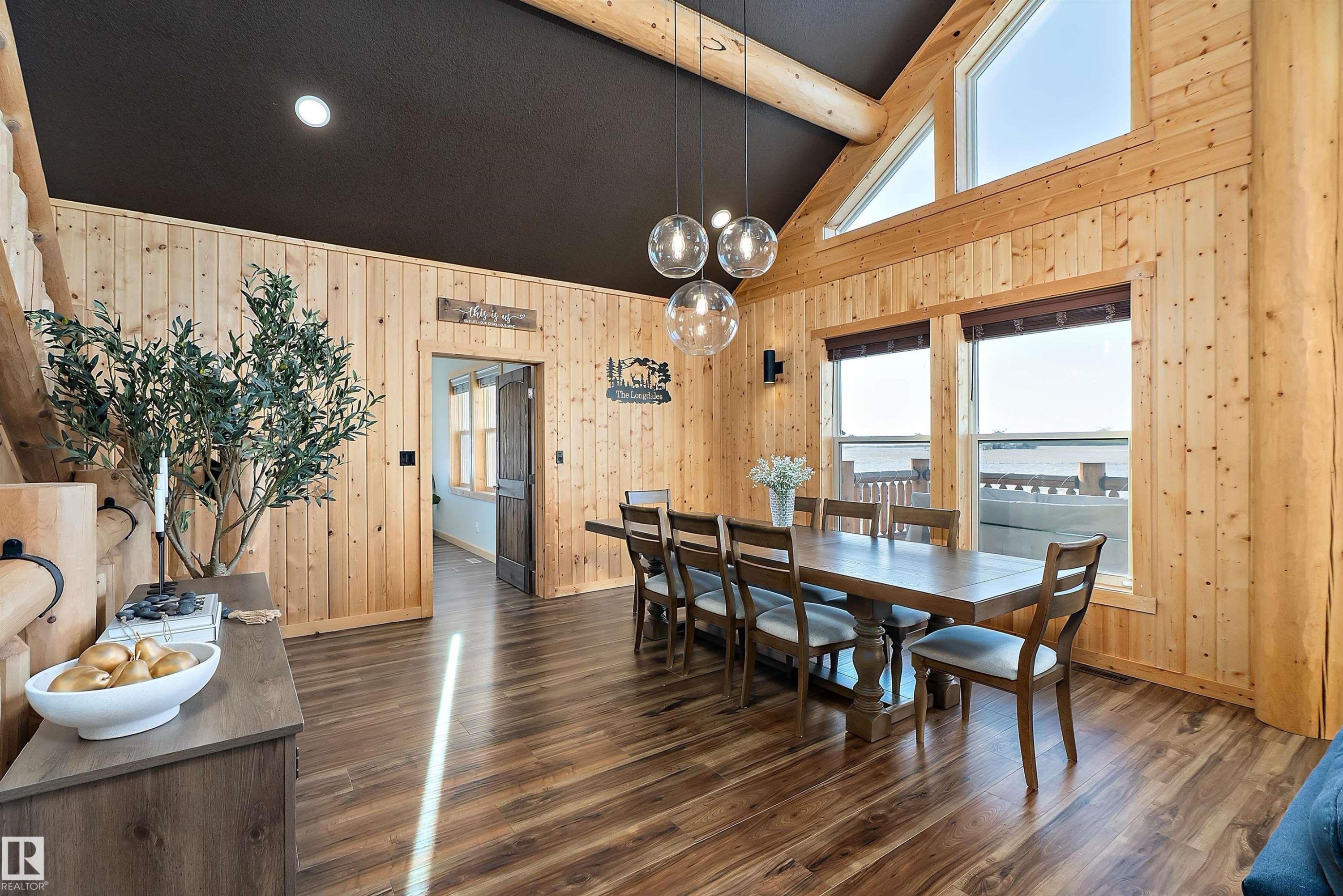 Dining area featuring dark wood-style floors, wood walls, a chandelier, and high vaulted ceiling - 19003 Twp Rd 522, Rural Beaver County, AB - Indoor Photo Showing Dining Room