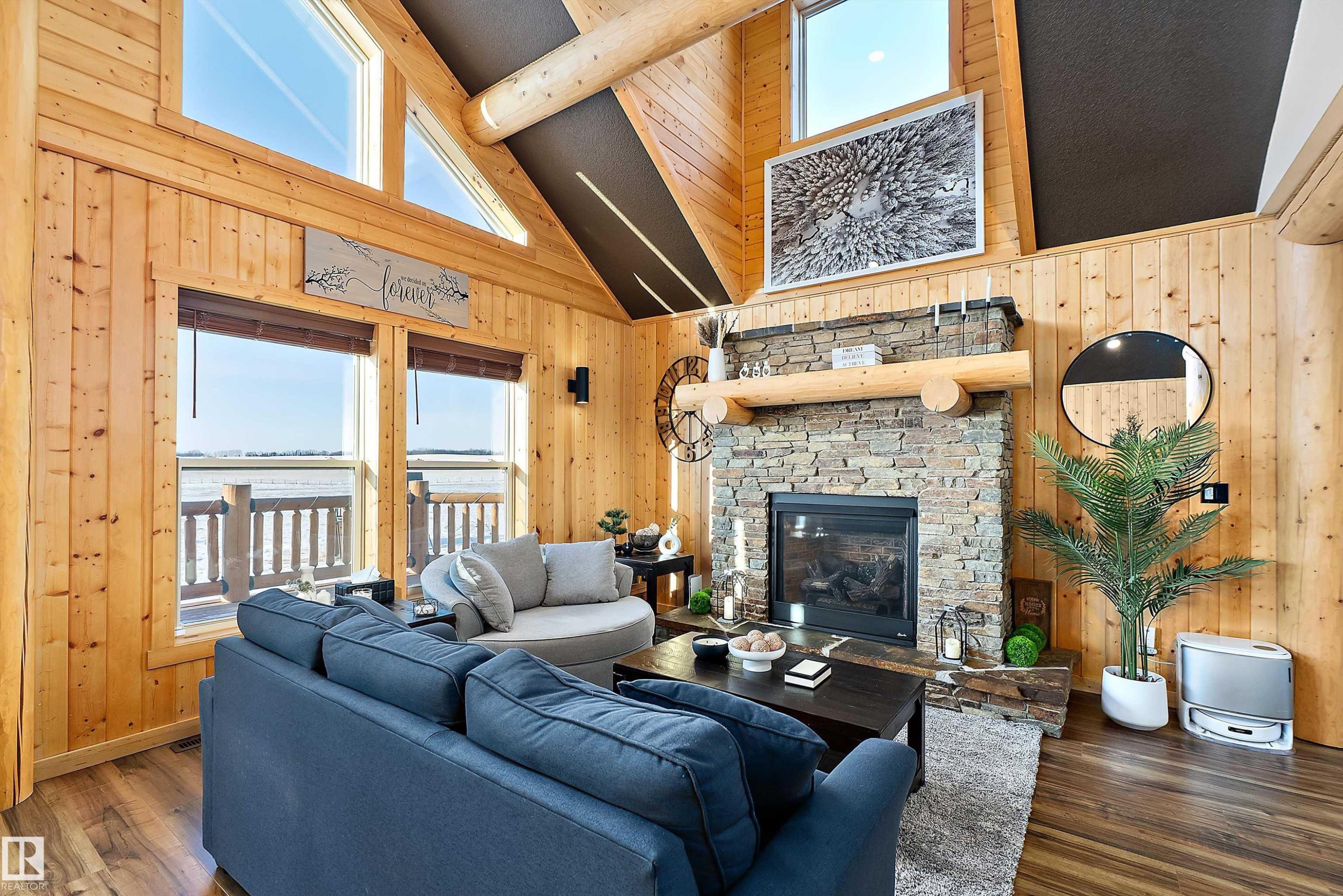Living area featuring wooden walls, high vaulted ceiling, a stone fireplace, dark wood-type flooring, and beam ceiling - 19003 Twp Rd 522, Rural Beaver County, AB - Indoor Photo Showing Living Room With Fireplace
