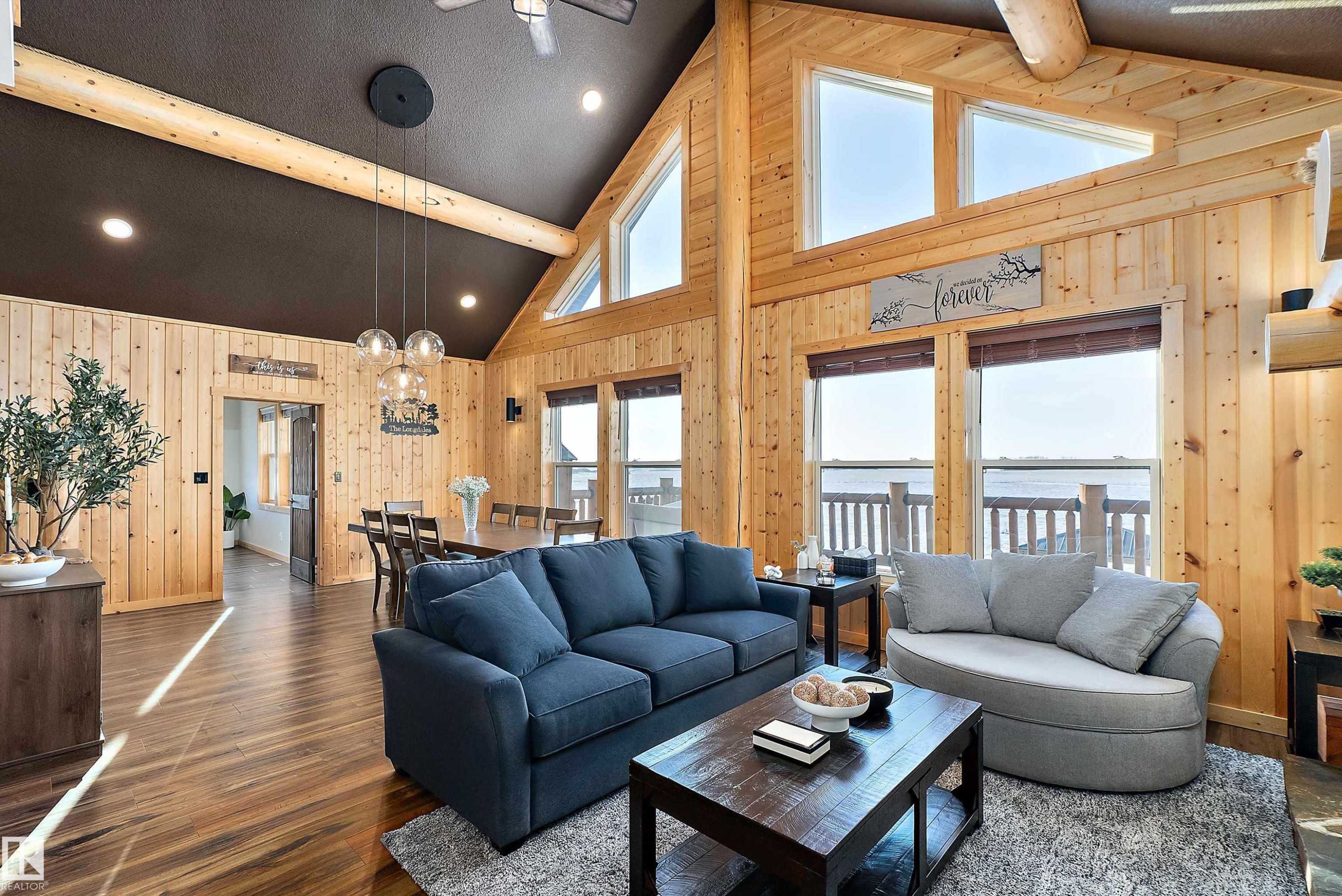 Living room with wood walls, dark wood-style flooring, high vaulted ceiling, beam ceiling, and a chandelier - 19003 Twp Rd 522, Rural Beaver County, AB - Indoor Photo Showing Living Room