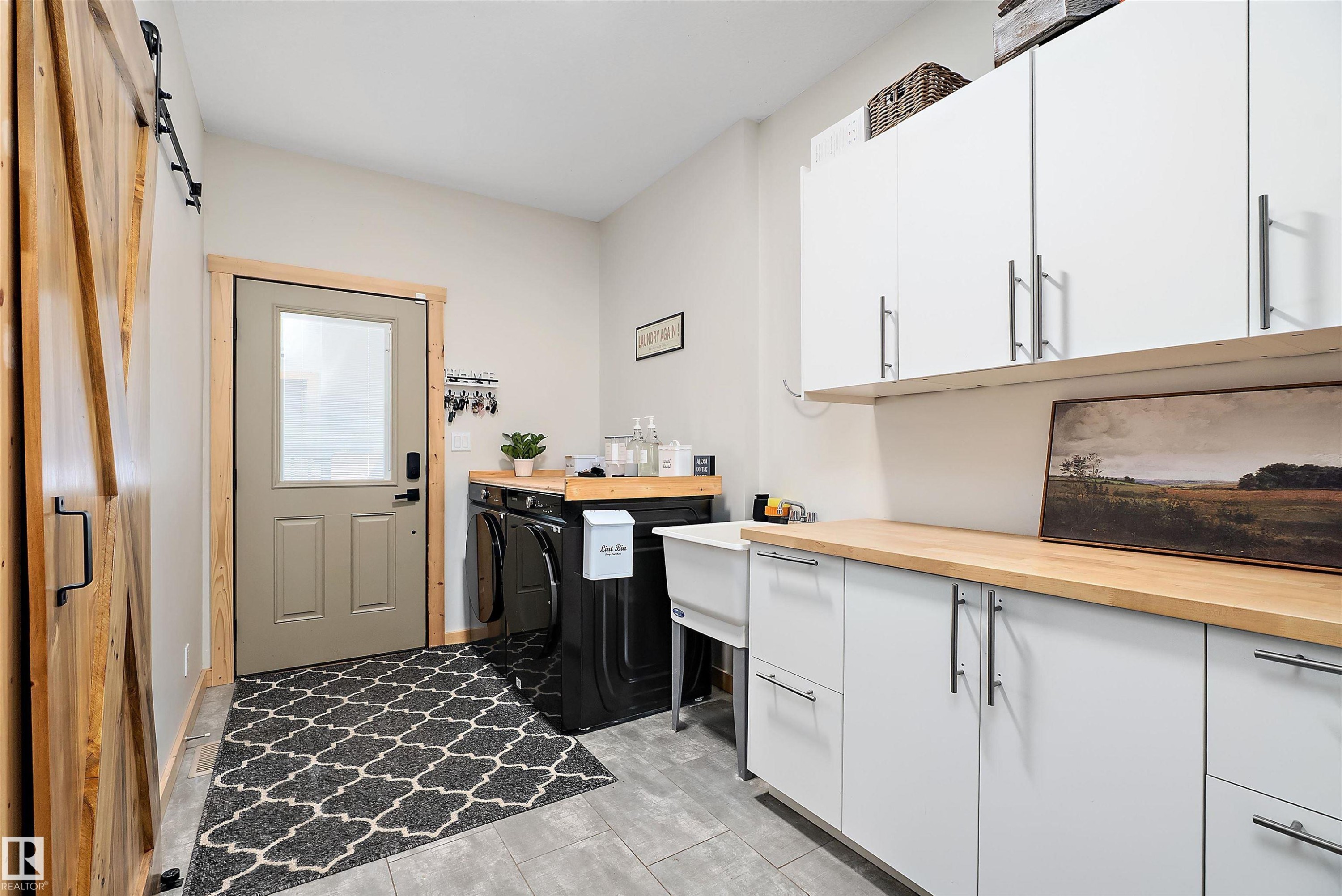 Washroom with a barn door, cabinet space, and washing machine and dryer - 19003 Twp Rd 522, Rural Beaver County, AB - Indoor