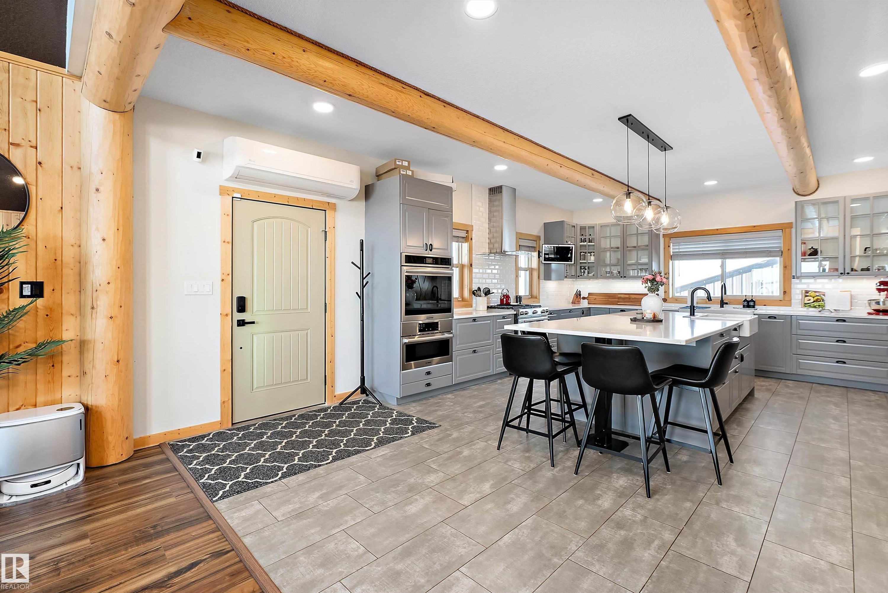 Kitchen featuring gray cabinets, decorative light fixtures, a kitchen bar, beam ceiling, and an island with sink - 19003 Twp Rd 522, Rural Beaver County, AB - Indoor