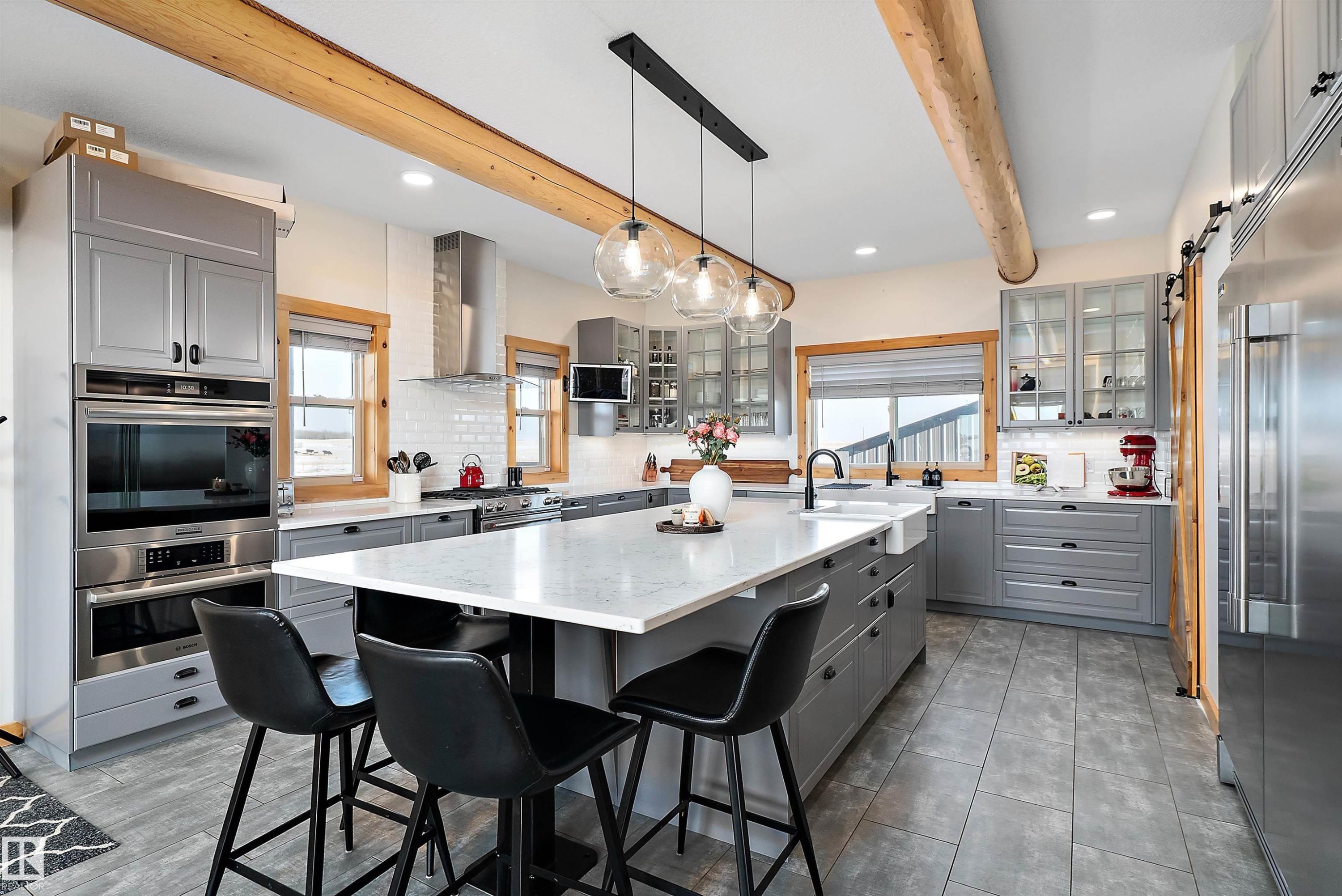 Kitchen with gray cabinets, decorative light fixtures, a barn door, beam ceiling, and tasteful backsplash - 19003 Twp Rd 522, Rural Beaver County, AB - Indoor Photo Showing Kitchen With Upgraded Kitchen