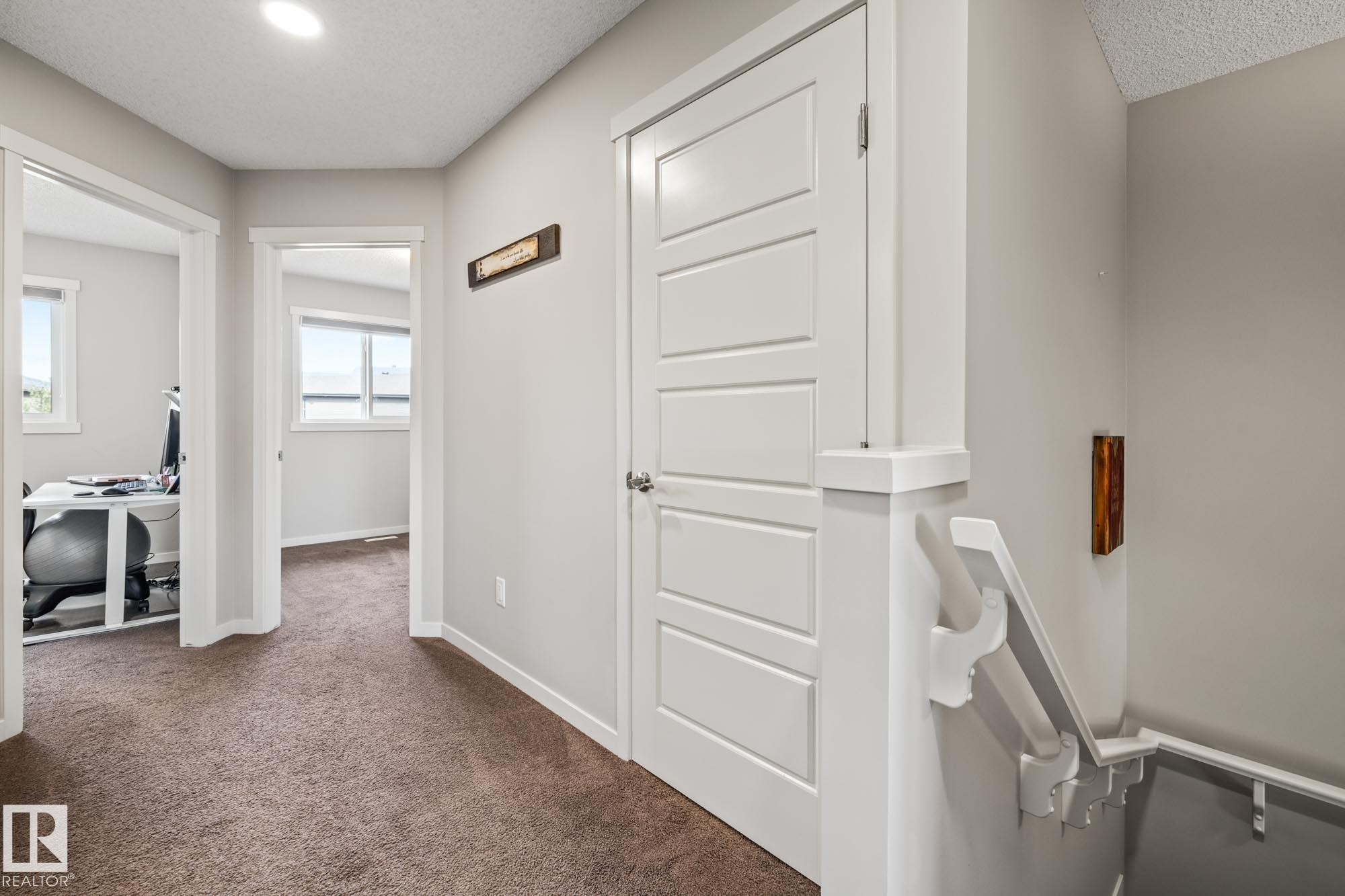 Hall with dark carpet, an office area, and a textured ceiling - 20110 27 Avenue, Edmonton, AB - Indoor Photo Showing Other Room