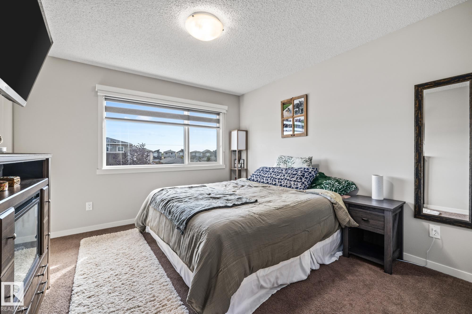 Bedroom with dark colored carpet and a textured ceiling - 20110 27 Avenue, Edmonton, AB - Indoor Photo Showing Bedroom