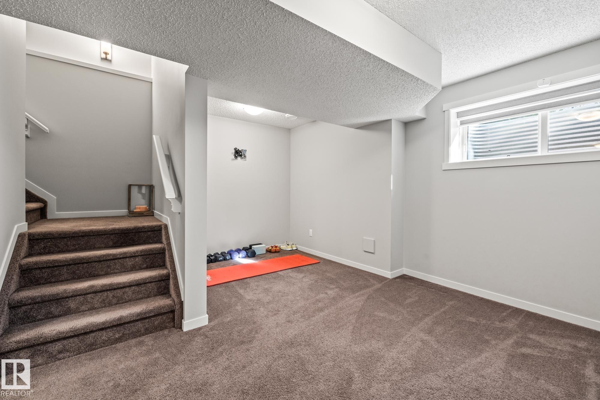 Below grade area featuring dark colored carpet, a textured ceiling, and stairs - 20110 27 Avenue, Edmonton, AB - Indoor Photo Showing Other Room