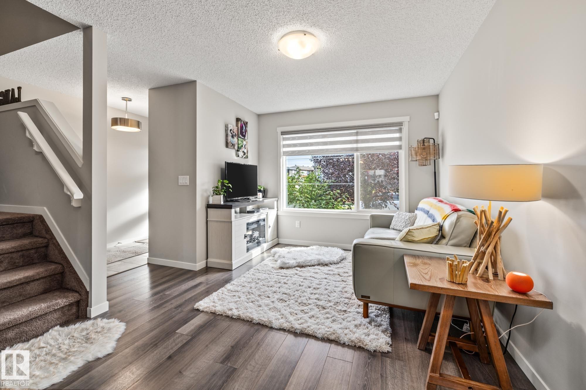 Living area with stairs, dark wood-style floors, and a textured ceiling - 20110 27 Avenue, Edmonton, AB - Indoor
