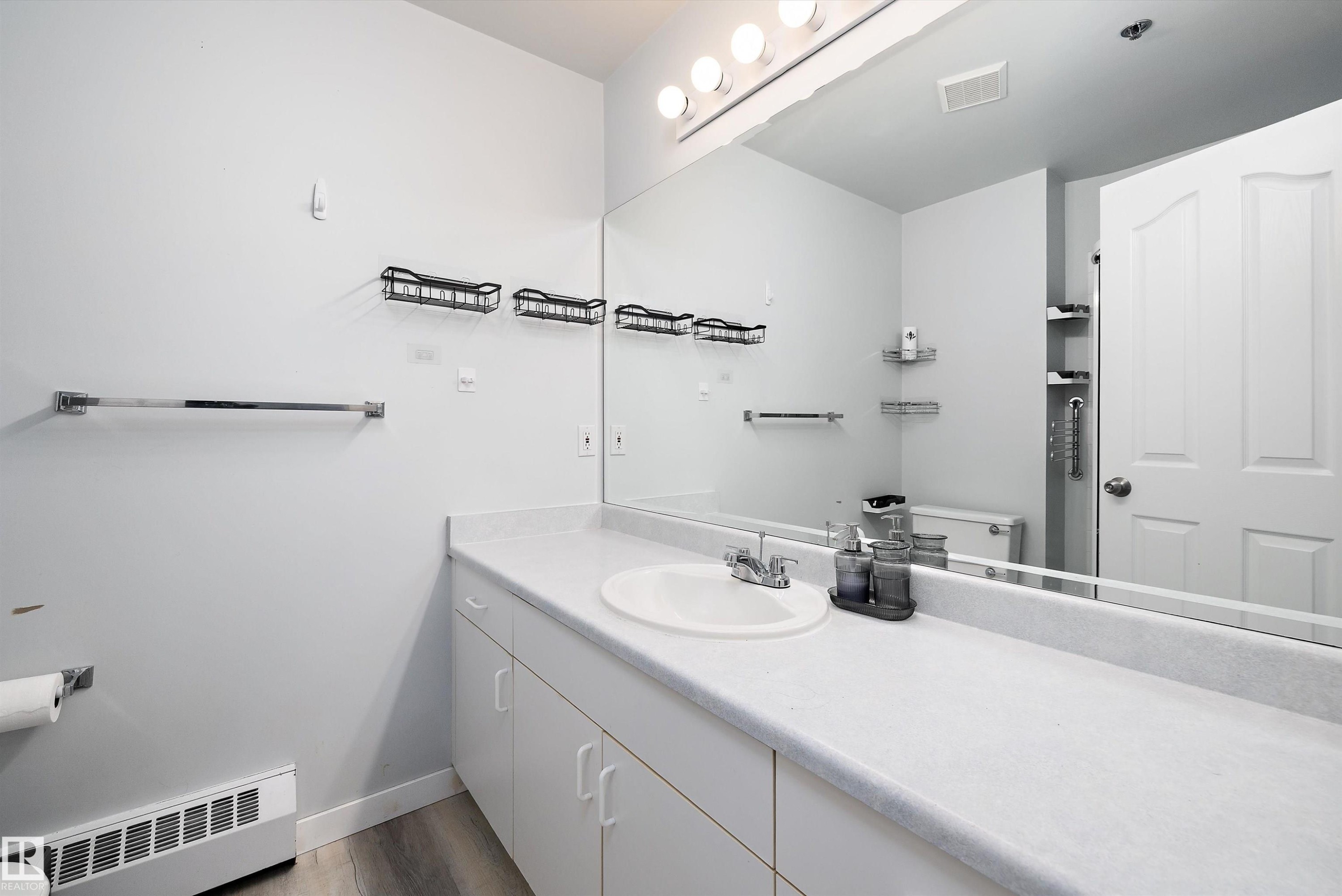 Bathroom featuring a baseboard heating unit, vanity, and dark wood-style floors - 205 10809 Saskatchewan Drive, Edmonton, AB - Indoor Photo Showing Bathroom