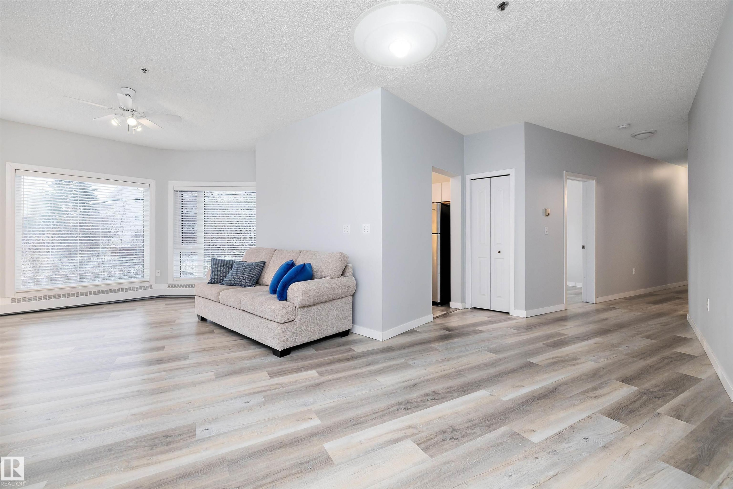 Living area with ceiling fan, light wood-style flooring, and a textured ceiling - 205 10809 Saskatchewan Drive, Edmonton, AB - Indoor Photo Showing Living Room