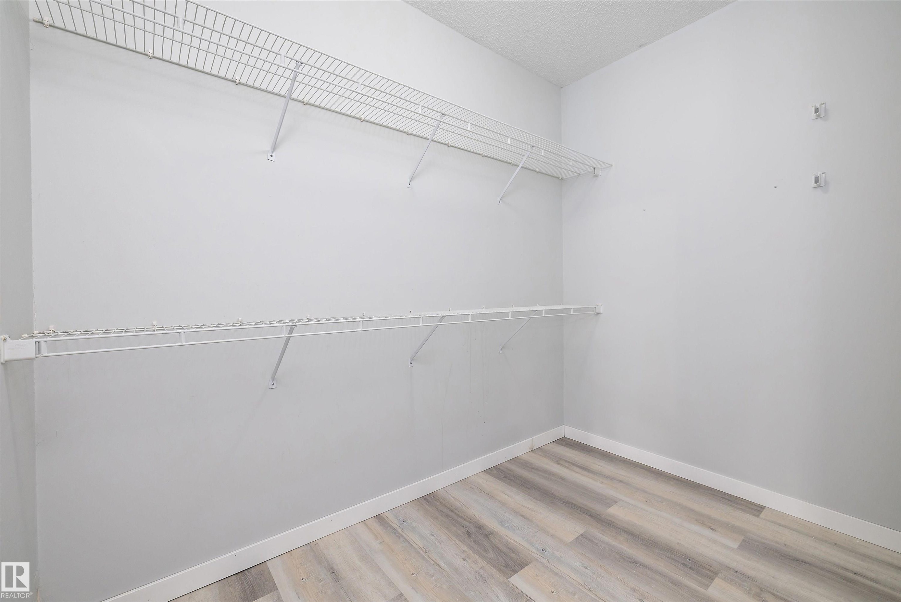Walk in closet with light wood finished floors - 205 10809 Saskatchewan Drive, Edmonton, AB - Indoor With Storage